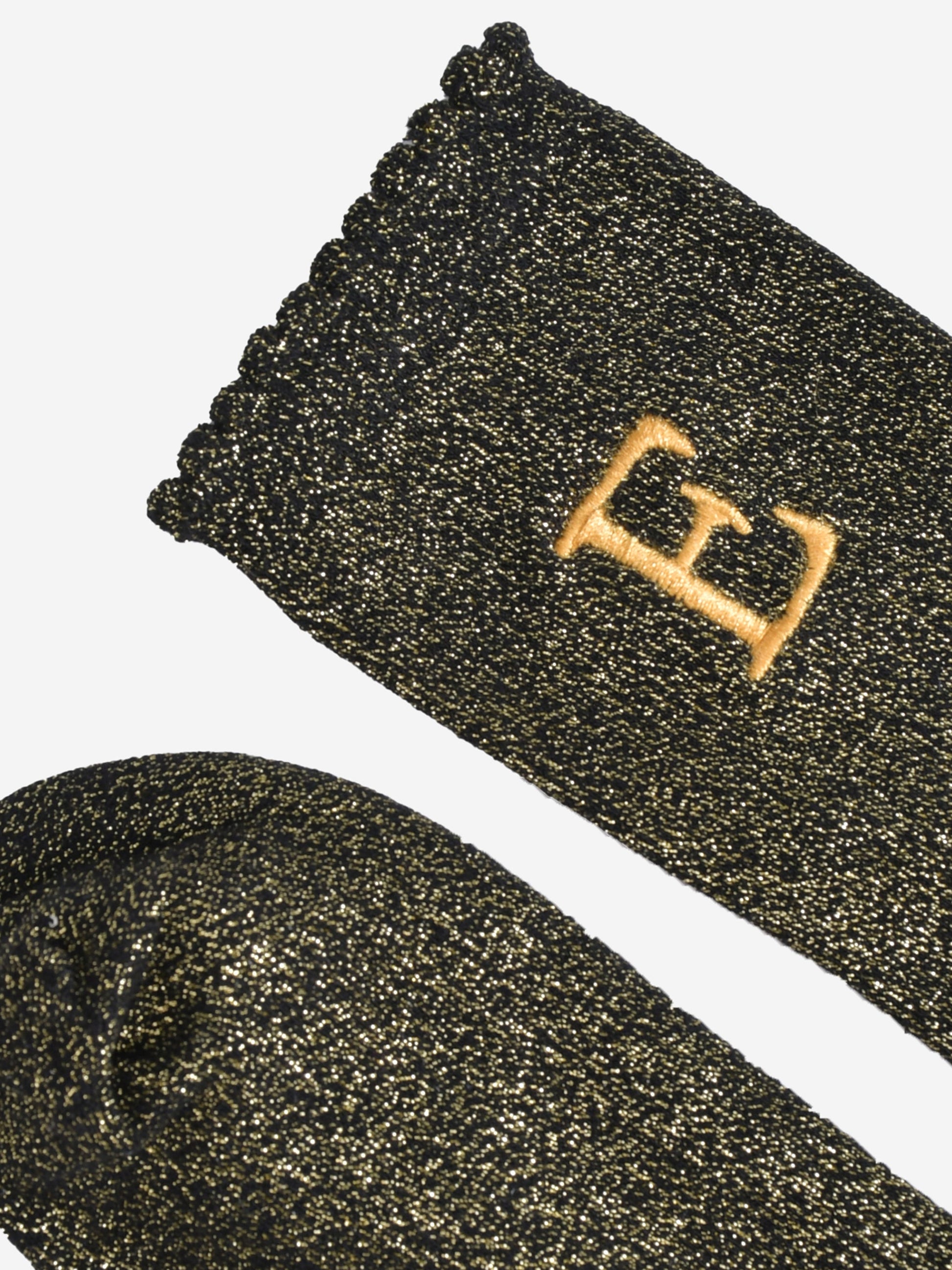 close up of the scalloped cuff on the socks, the toe is the same black and gold as the rest of the socks