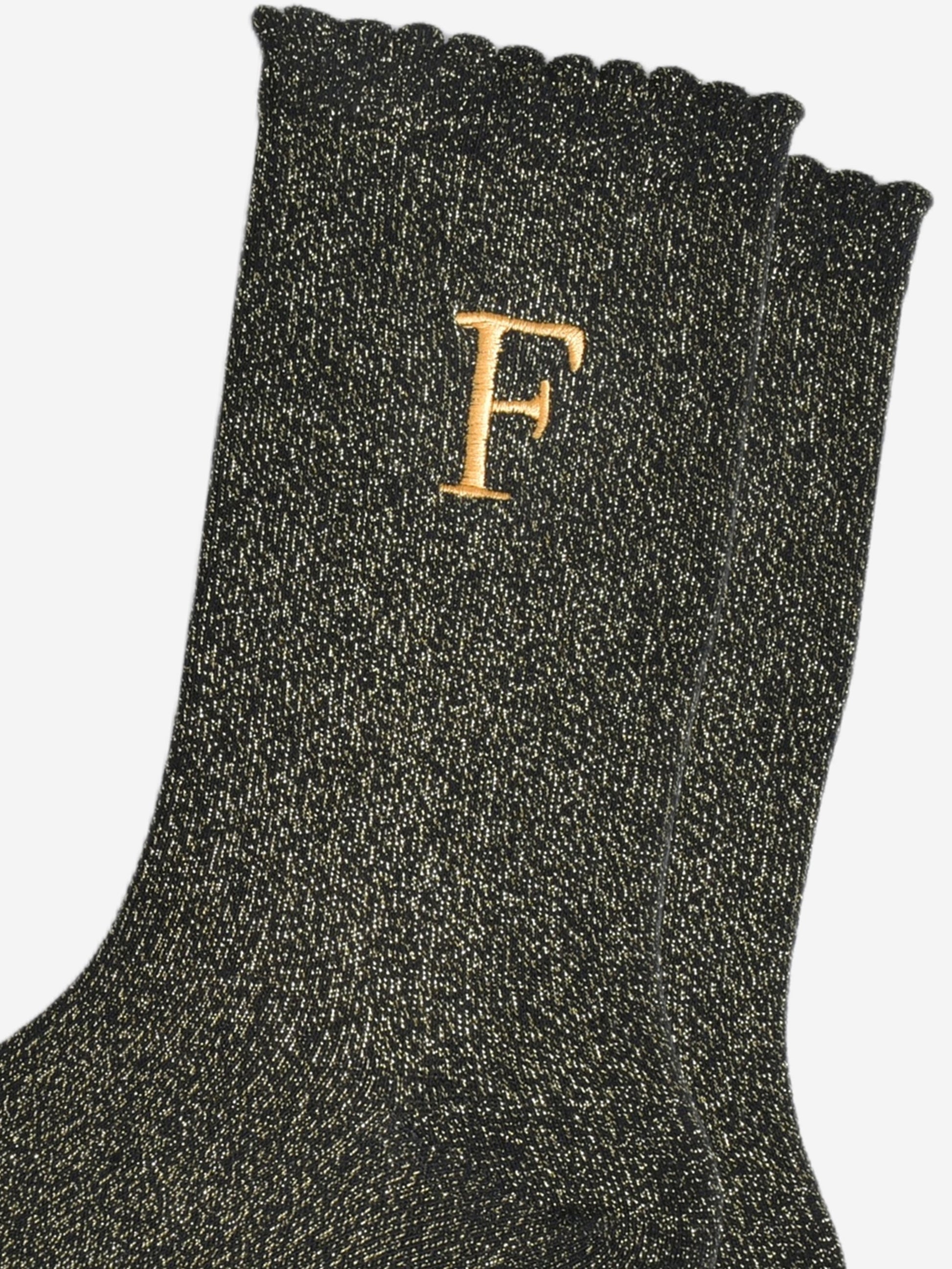 close up of the gold embroidered capital letter f on the ankle of the socks