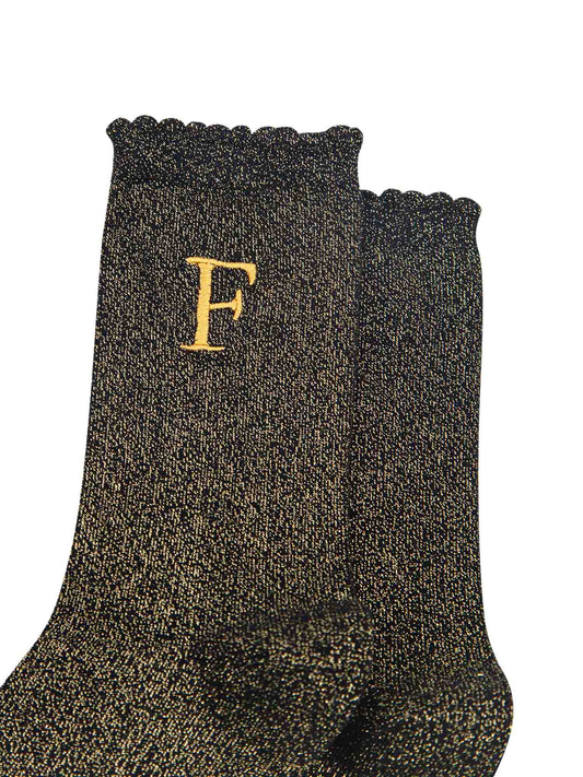 close up of the gold embroidered capital letter f on the ankle of the socks
