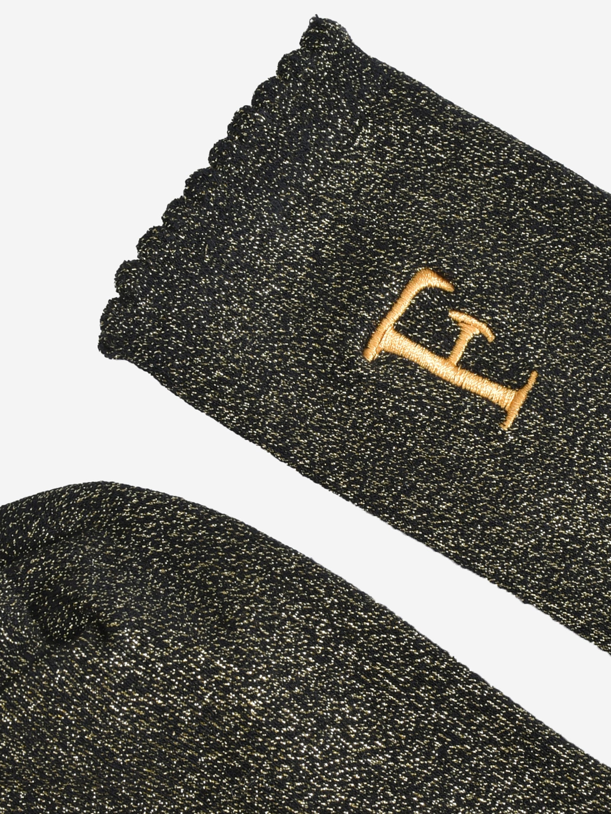 close up of the scalloped cuff on the socks, the toe is the same black and gold as the rest of the socks