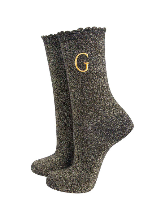 black ankle socks with a scalloped cuff, with an all over gold glitter sparkle and an embroidered gold letter g on the ankle