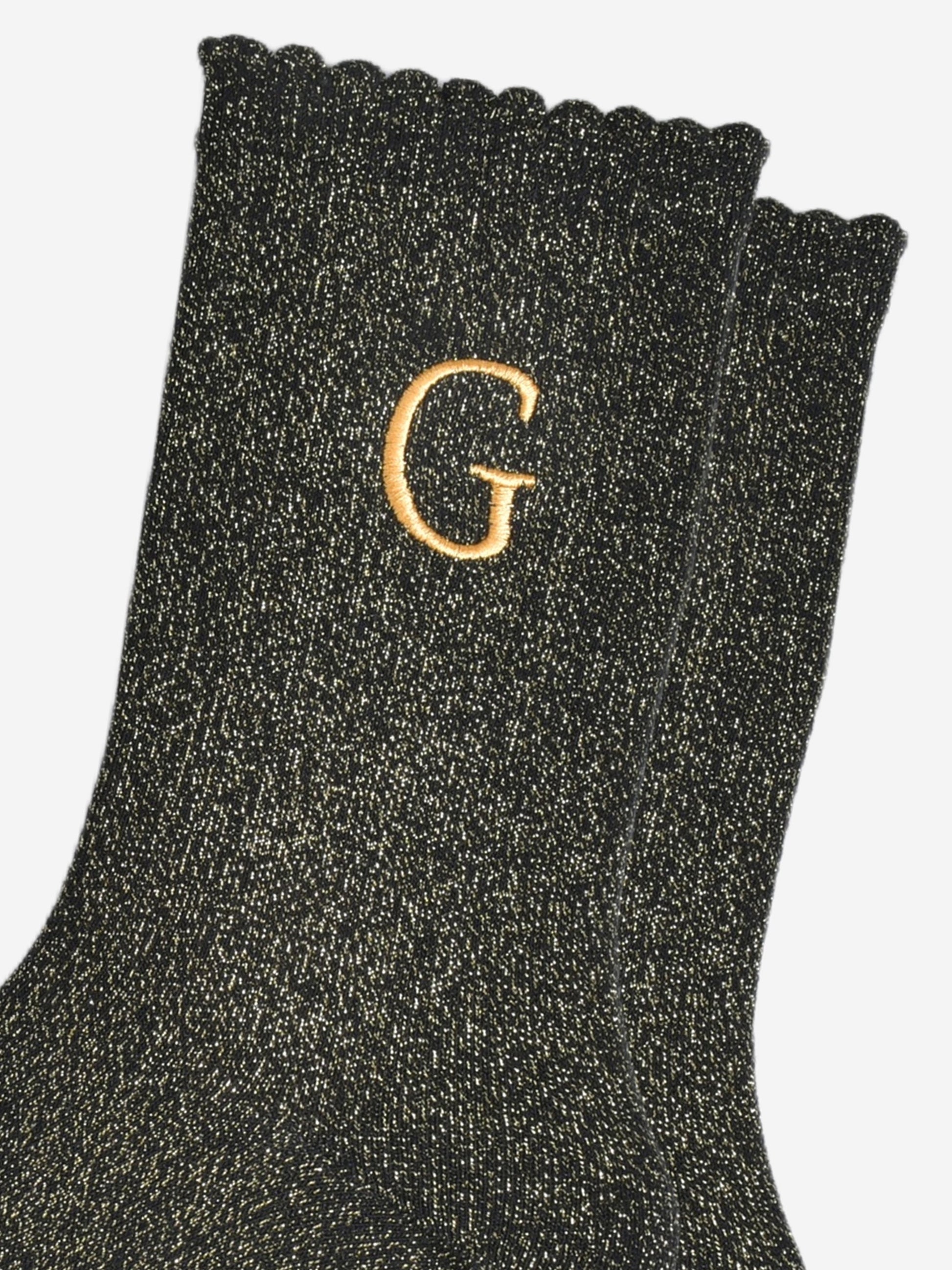 close up of the gold embroidered capital letter g on the ankle of the socks