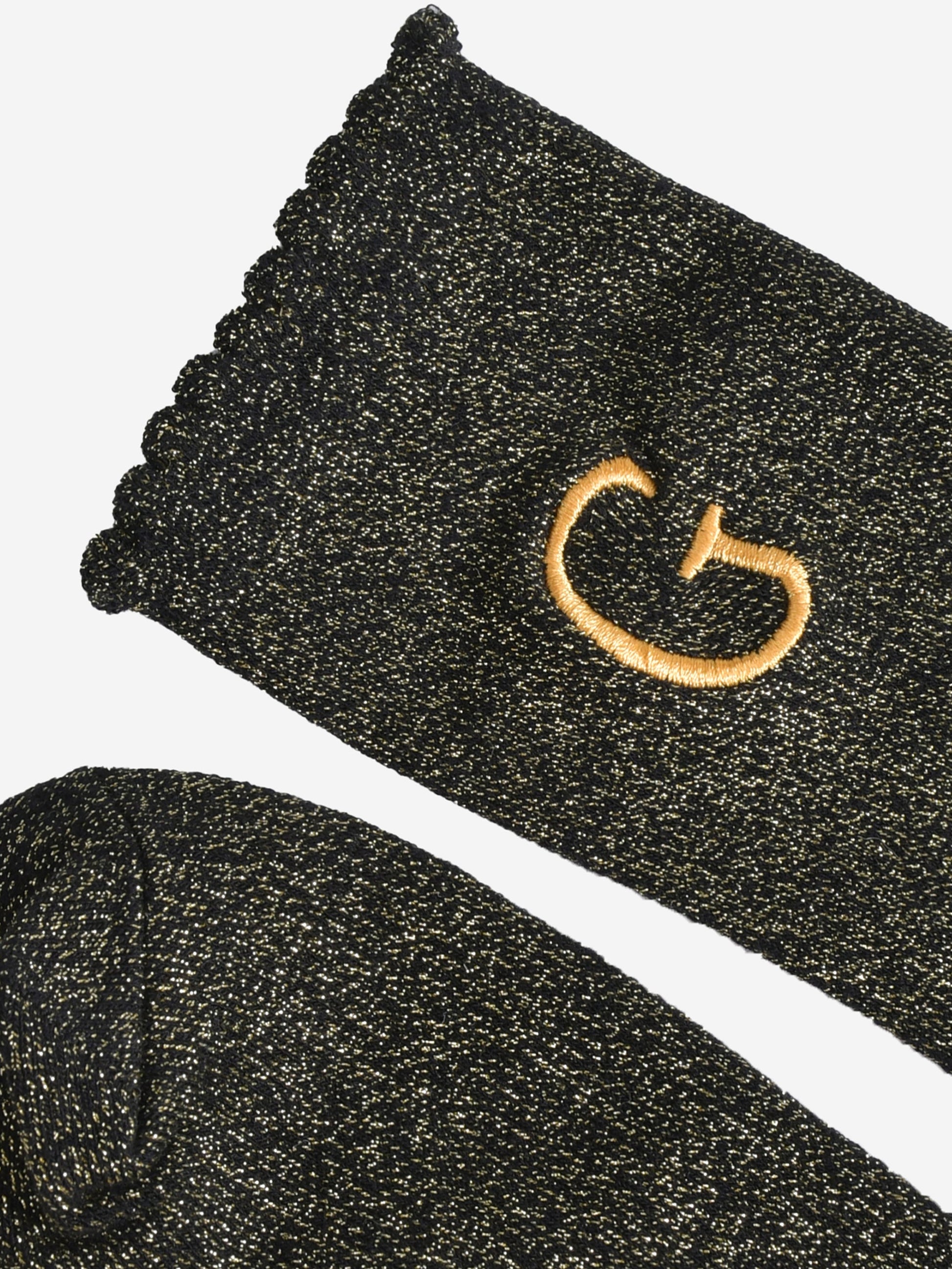 close up of the scalloped cuff on the socks, the toe is the same black and gold as the rest of the socks