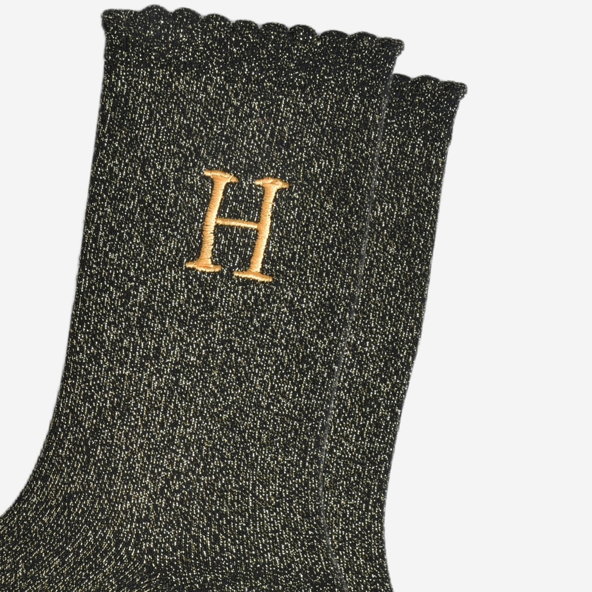 close up of the gold embroidered capital letter h on the ankle of the socks