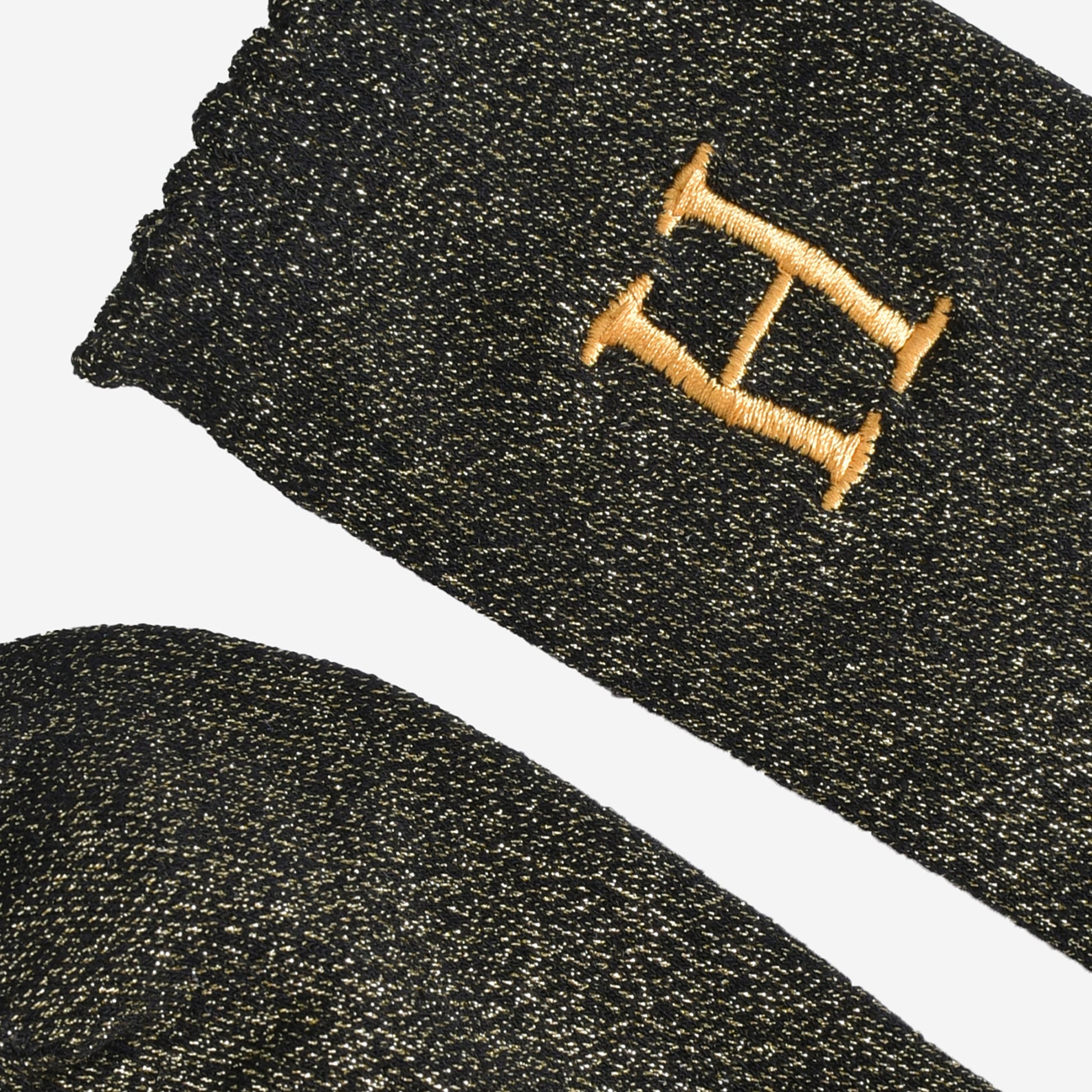 close up of the scalloped cuff on the socks, the toe is the same black and gold as the rest of the socks