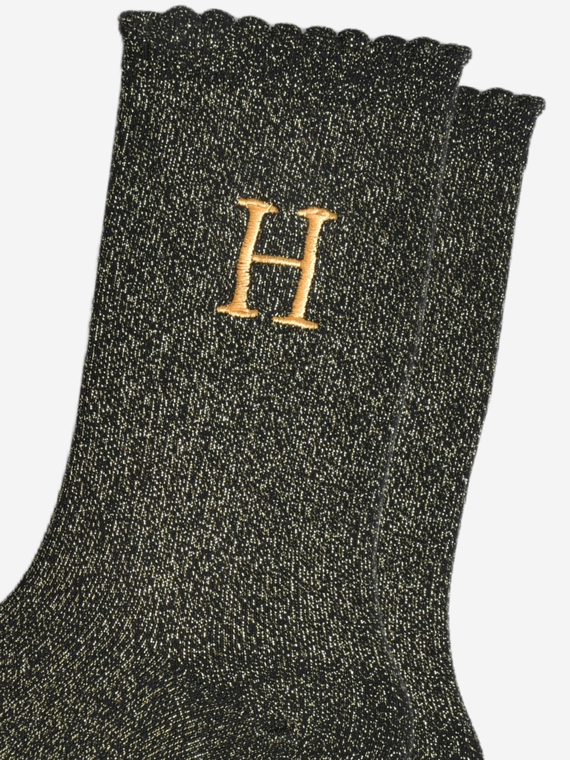 close up of the gold embroidered capital letter h on the ankle of the socks