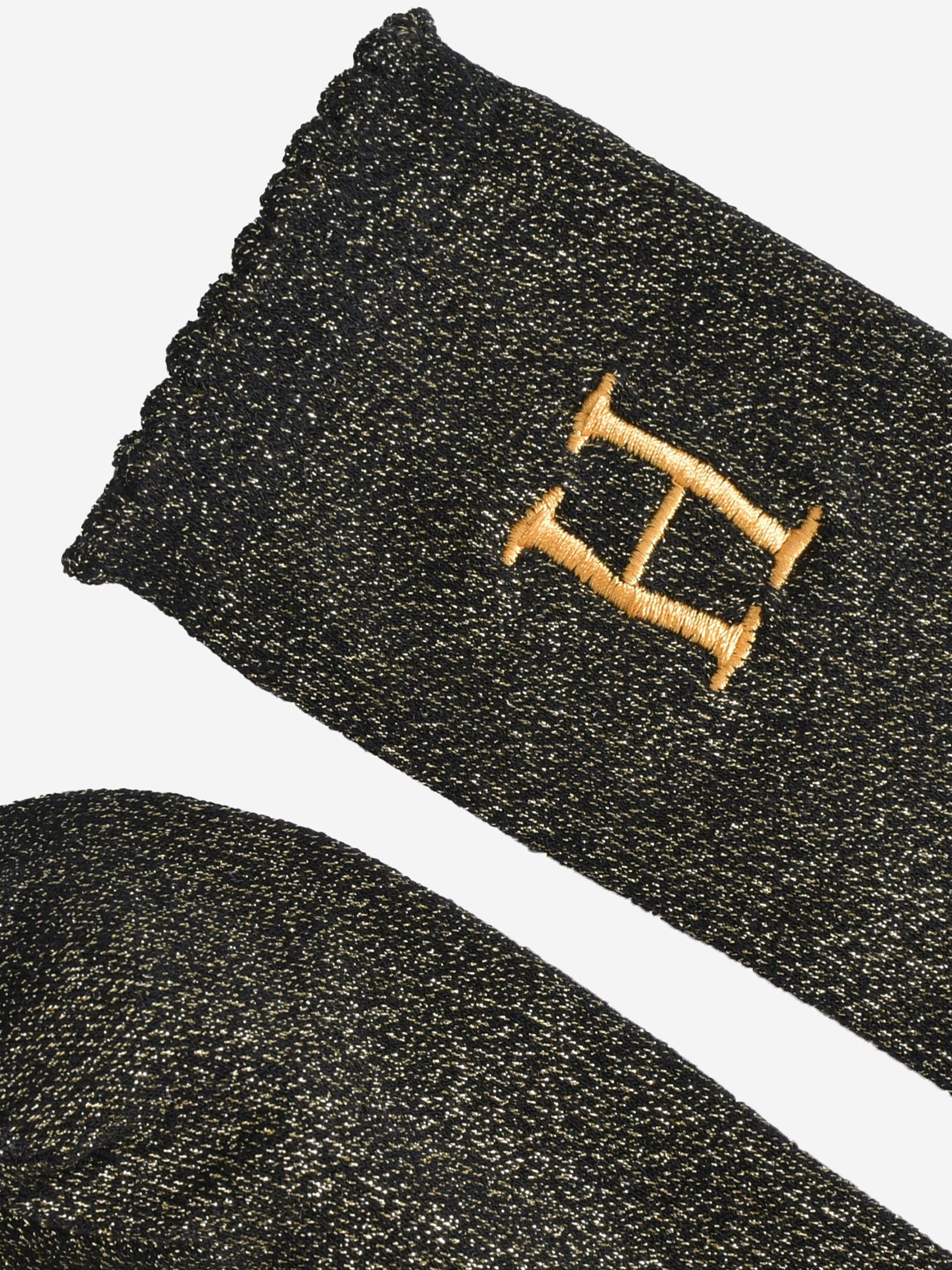 close up of the scalloped cuff on the socks, the toe is the same black and gold as the rest of the socks