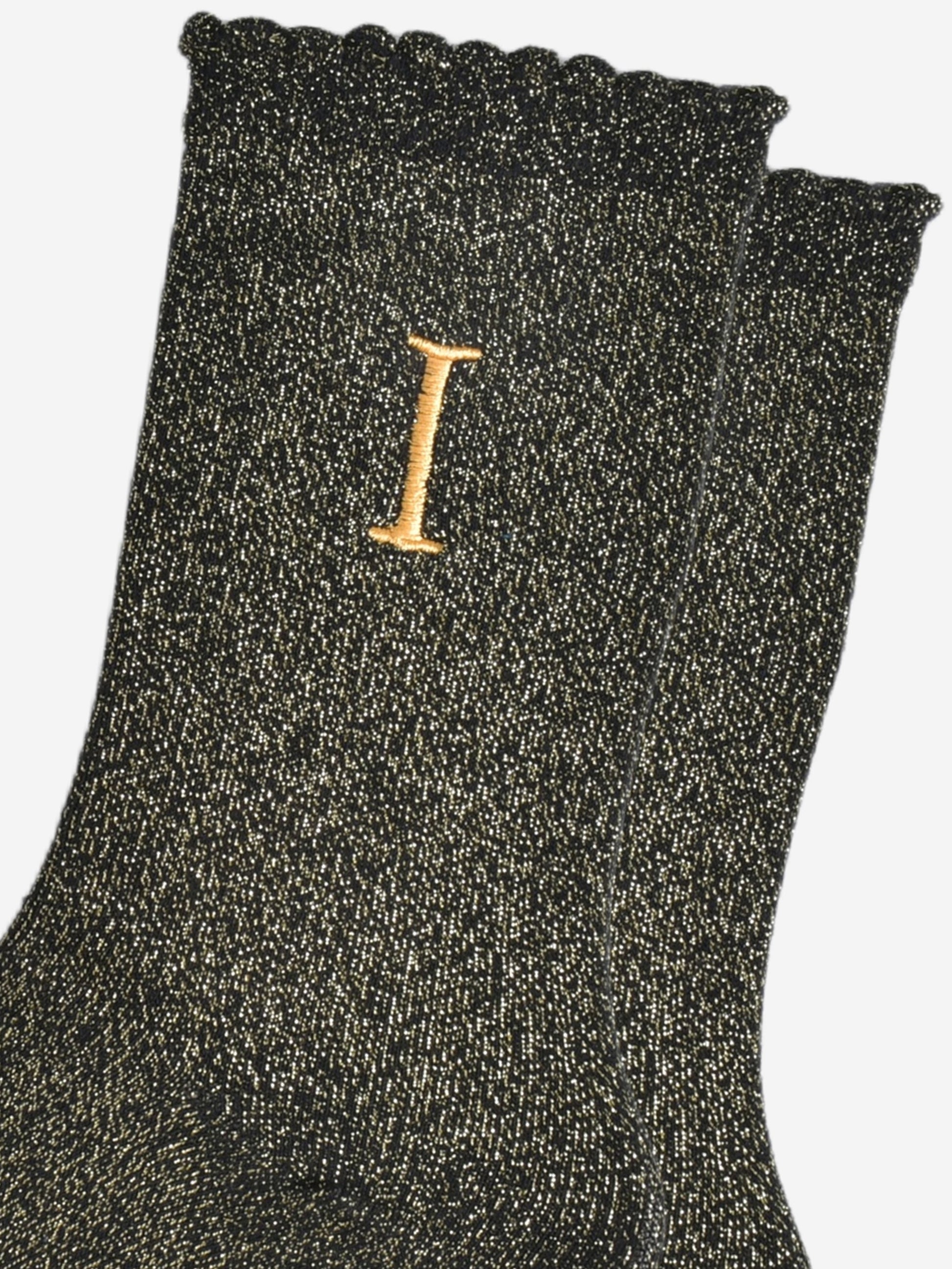 close up of the gold embroidered capital letter i on the ankle of the socks