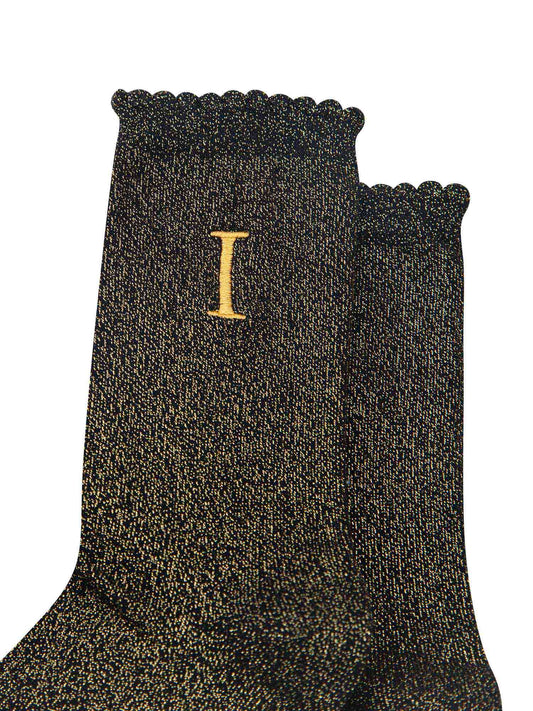 close up of the gold embroidered capital letter i on the ankle of the socks