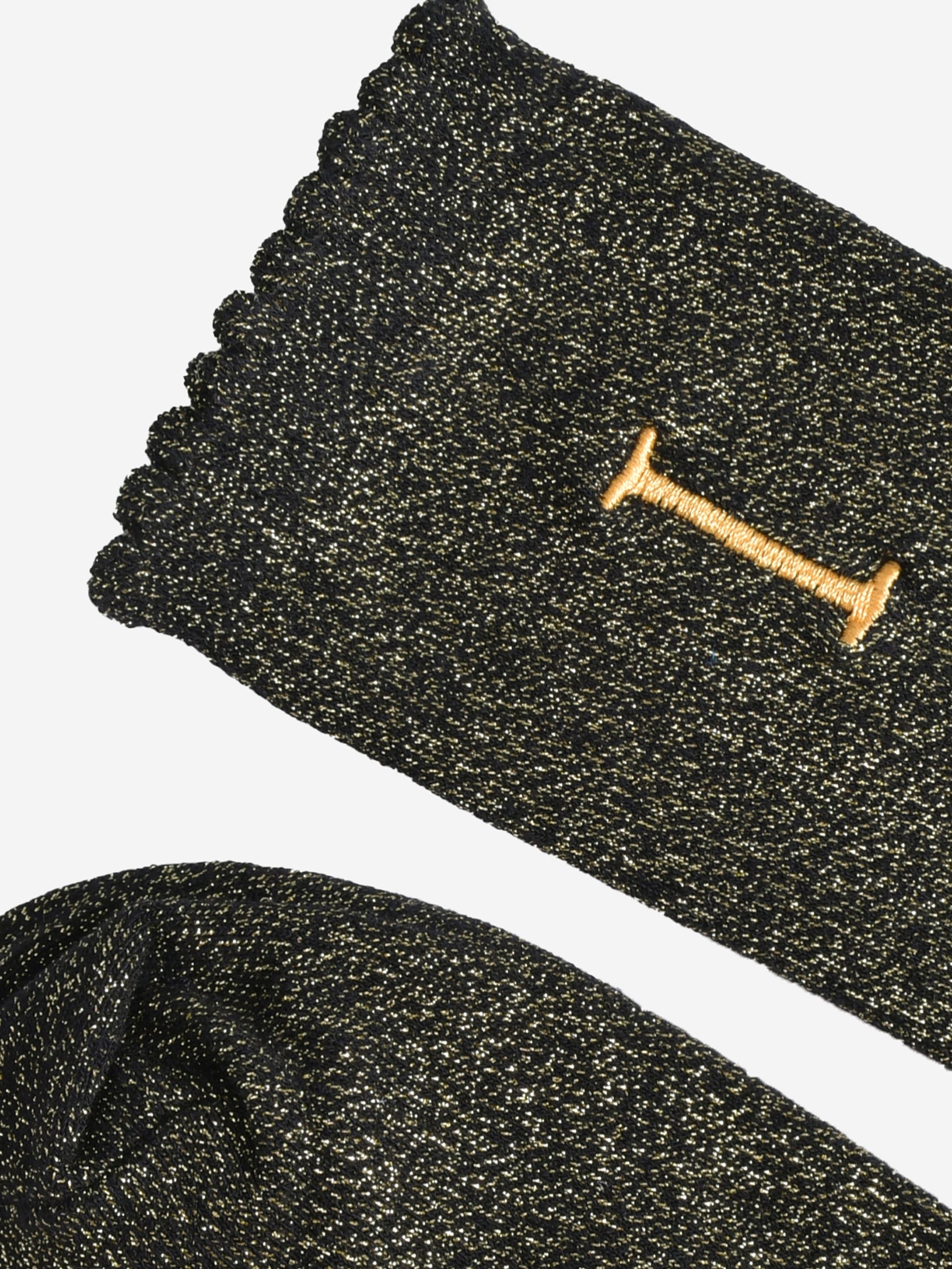 close up of the scalloped cuff on the socks, the toe is the same black and gold as the rest of the socks