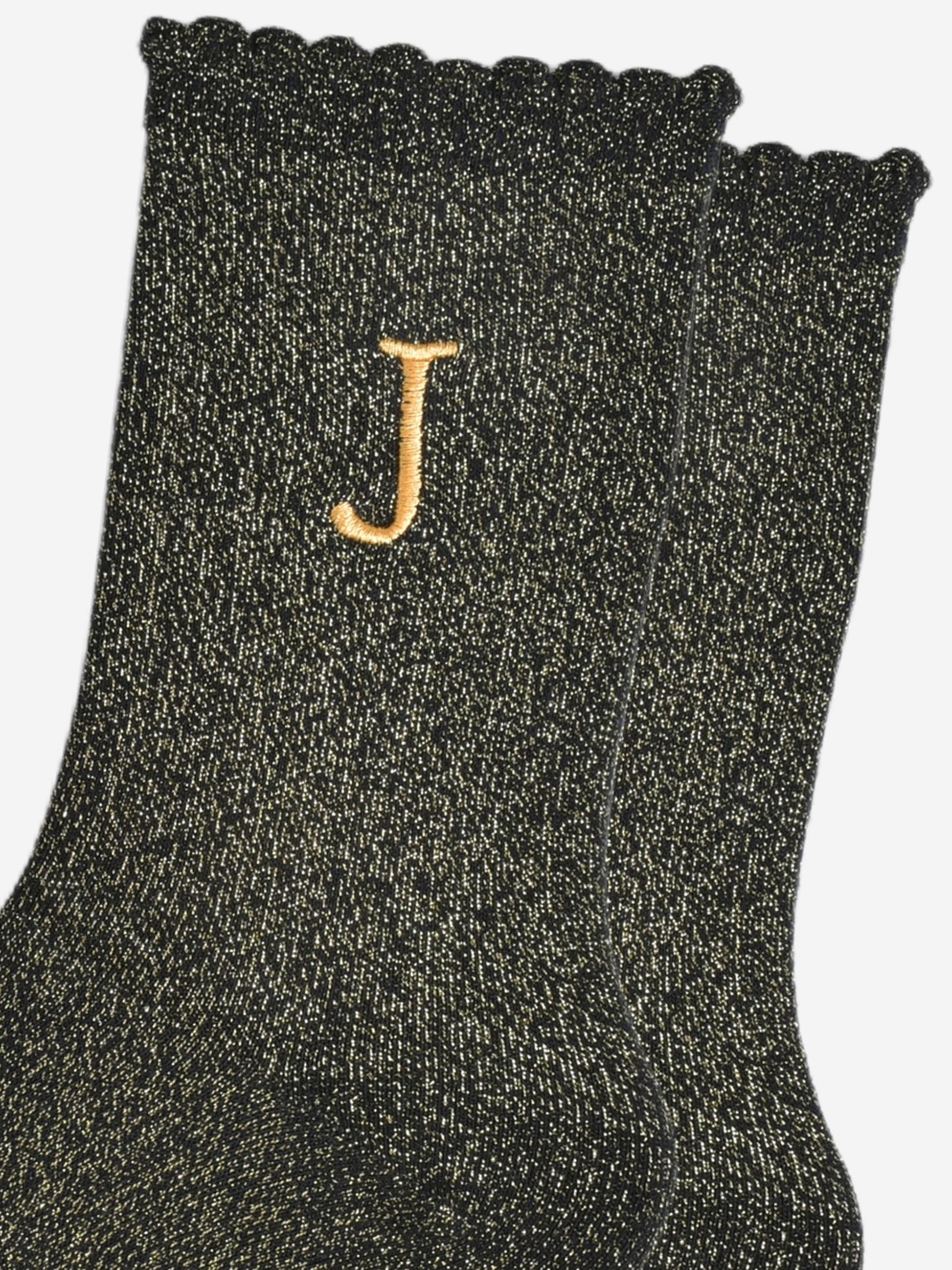 close up of the gold embroidered capital letter j on the ankle of the socks
