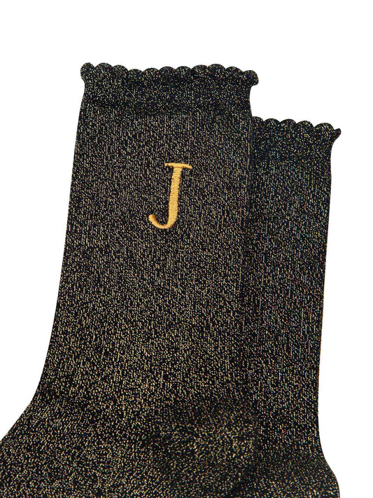 close up of the gold embroidered capital letter j on the ankle of the socks