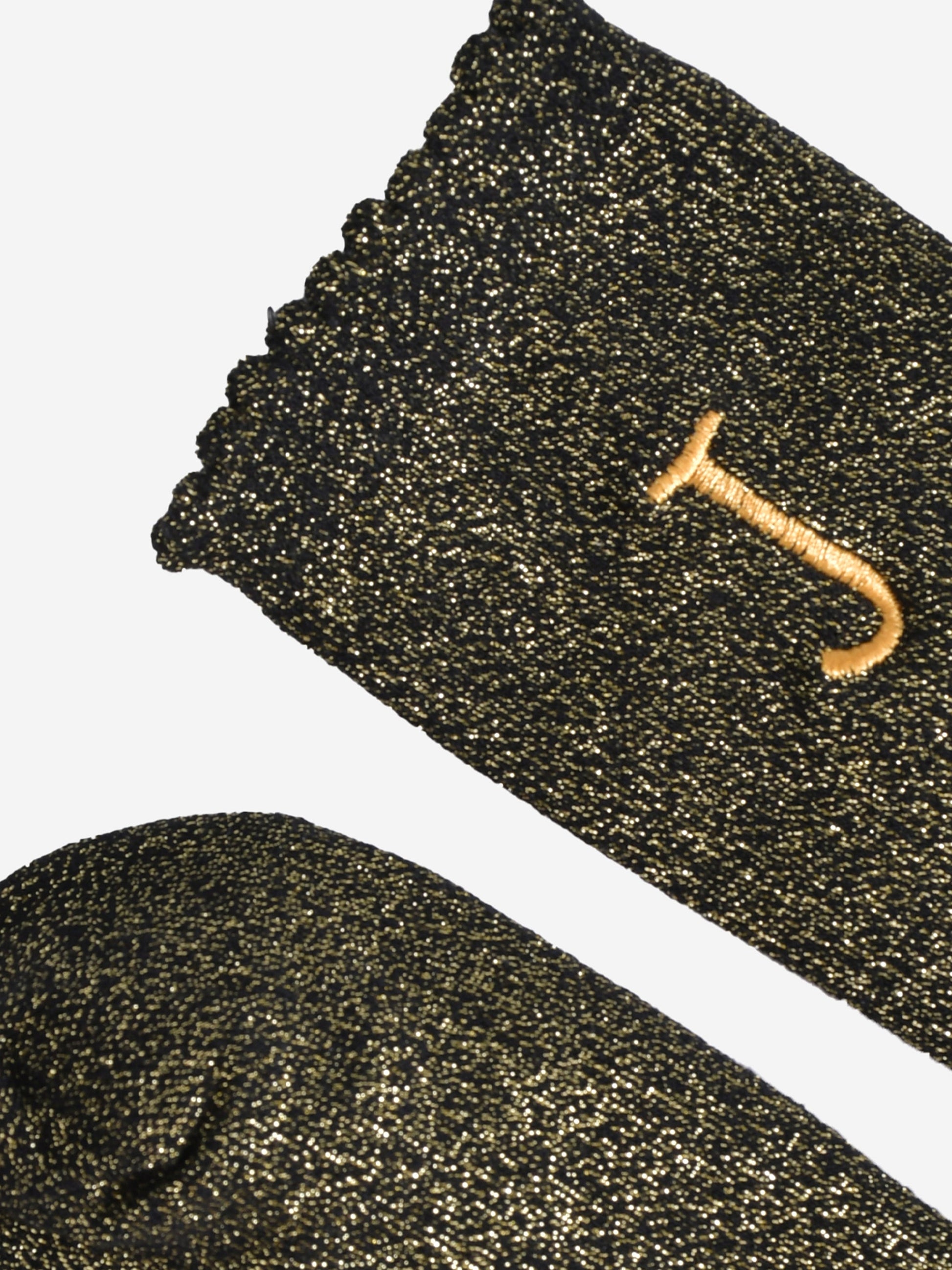 close up of the scalloped cuff on the socks, the toe is the same black and gold as the rest of the socks