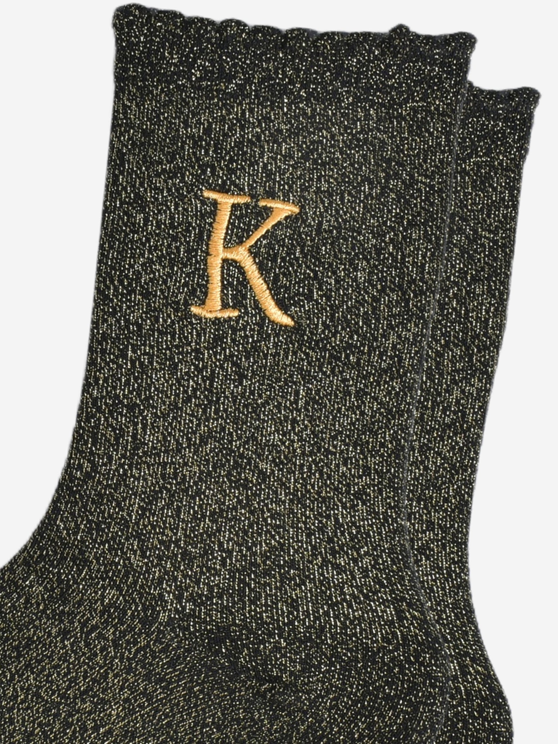 close up of the gold embroidered capital letter k on the ankle of the socks