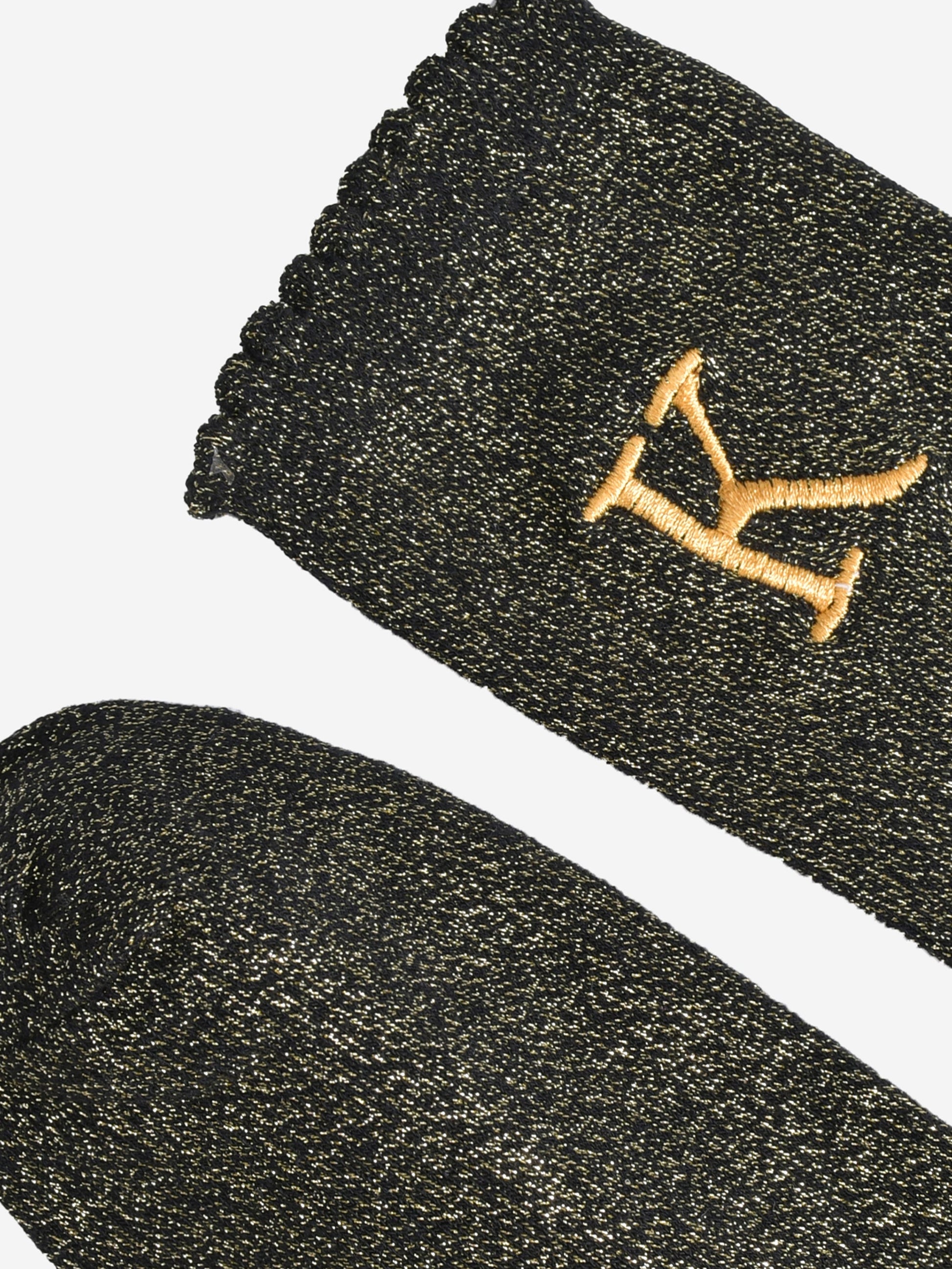 close up of the scalloped cuff on the socks, the toe is the same black and gold as the rest of the socks