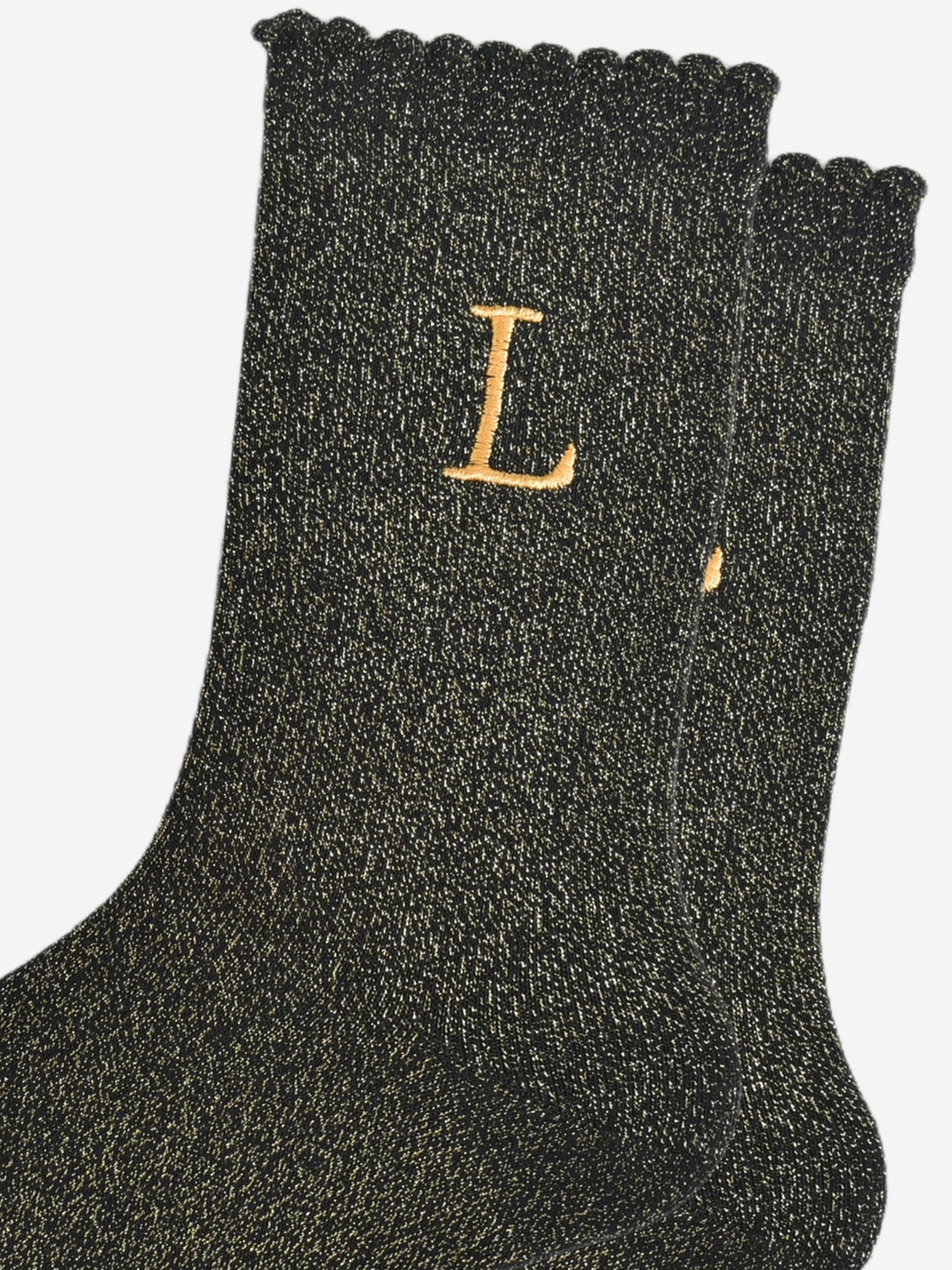 close up of the gold embroidered capital letter l on the ankle of the socks