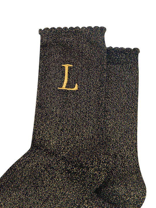 close up of the gold embroidered capital letter l on the ankle of the socks