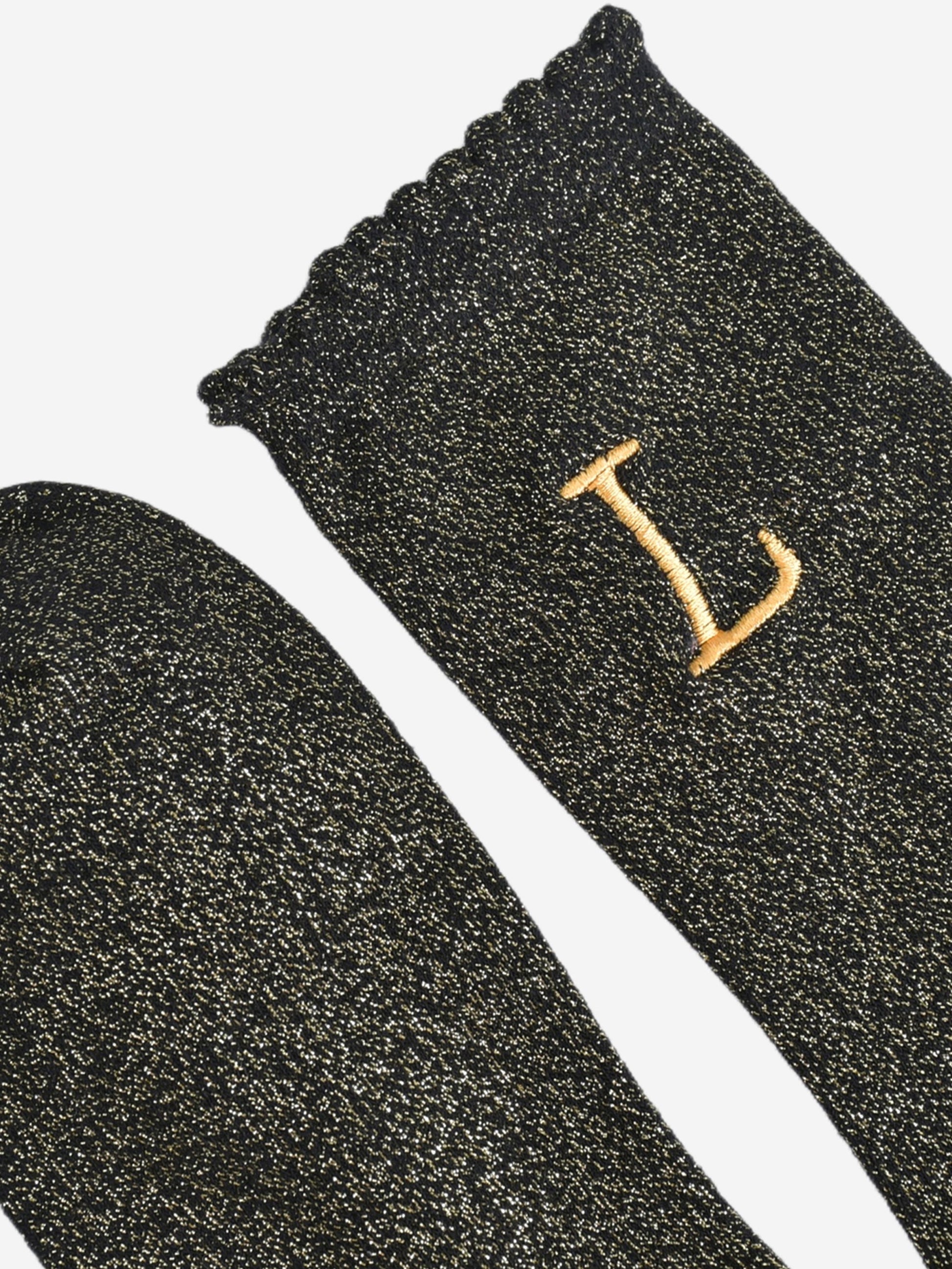 close up of the scalloped cuff on the socks, the toe is the same black and gold as the rest of the socks