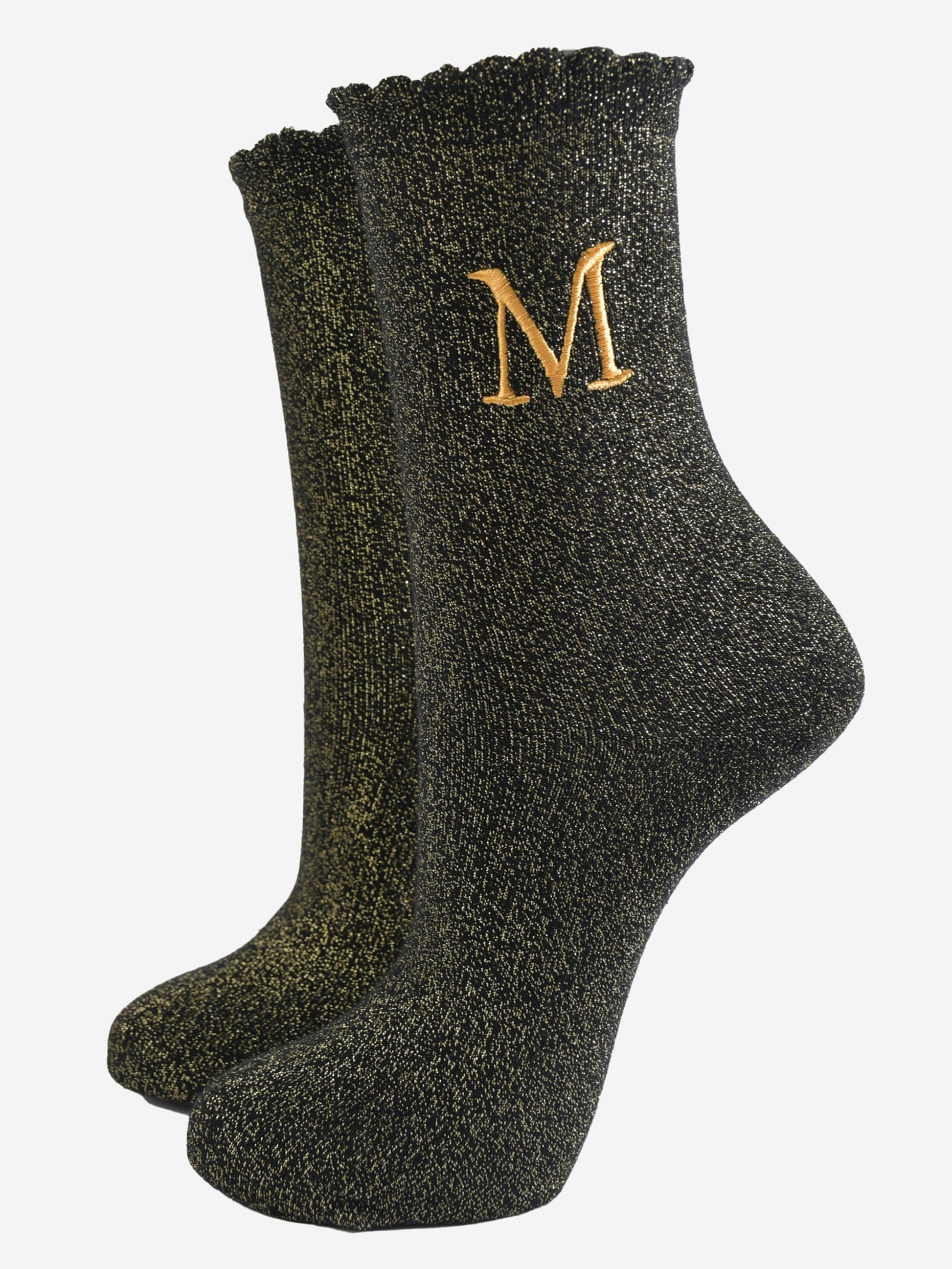 black ankle socks with a scalloped cuff, with an all over gold glitter sparkle and an embroidered gold letter m on the ankle