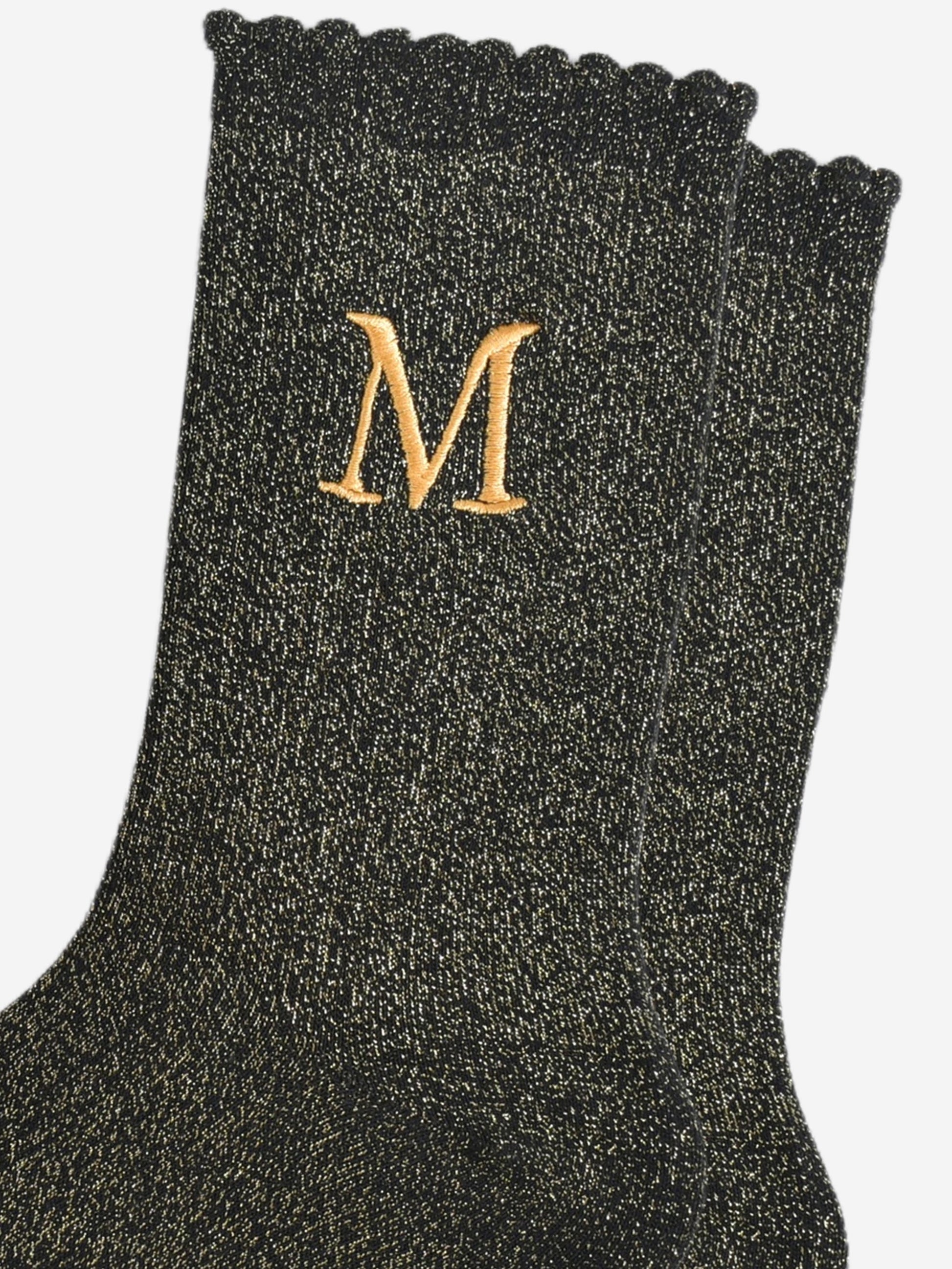 close up of the gold embroidered capital letter m on the ankle of the socks