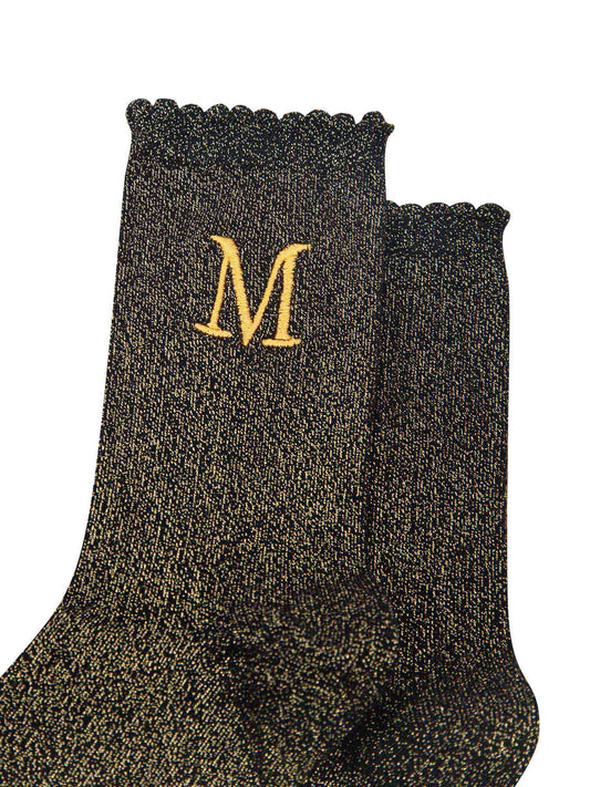 close up of the gold embroidered capital letter m on the ankle of the socks