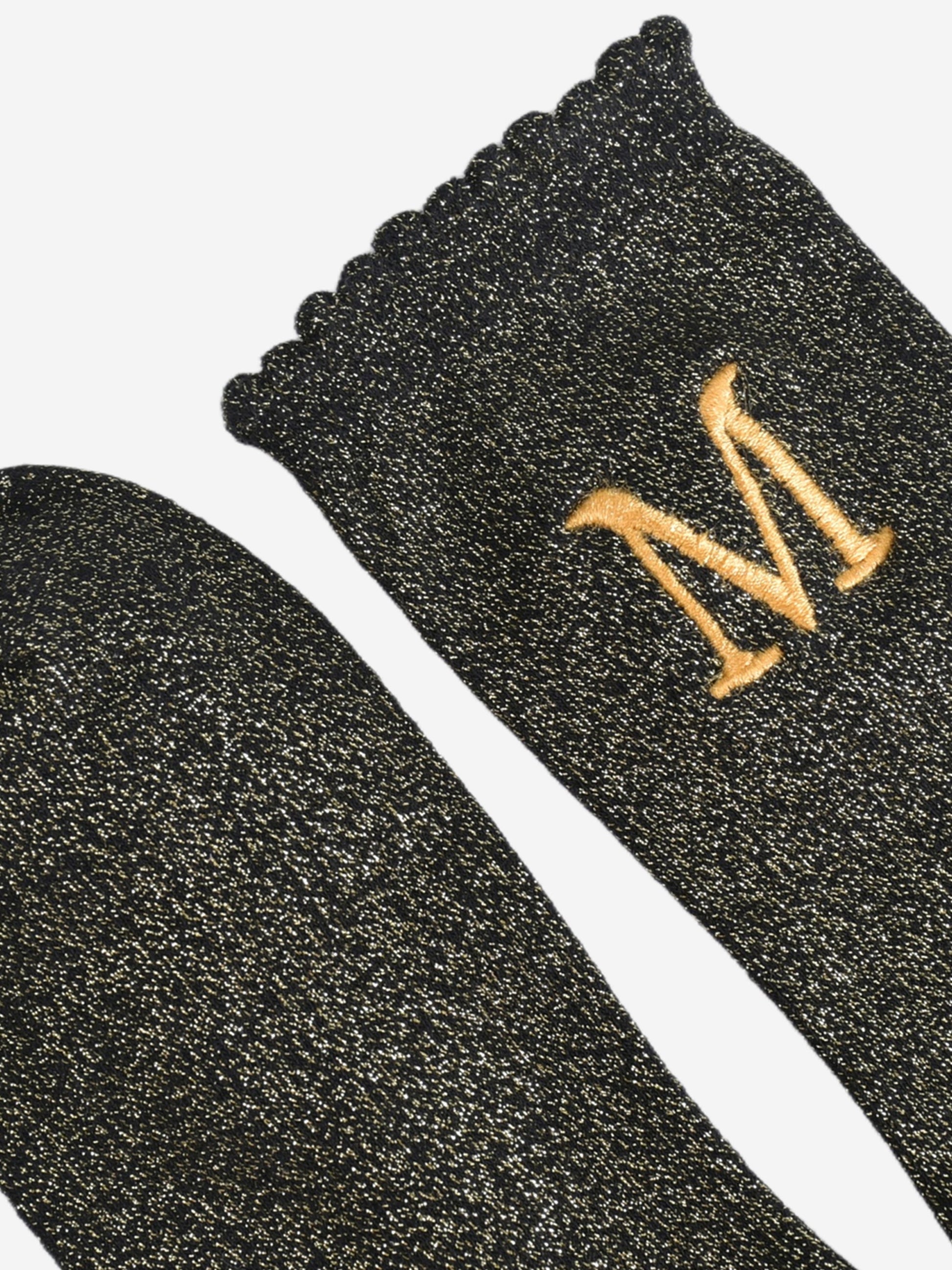 close up of the scalloped cuff on the socks, the toe is the same black and gold as the rest of the socks