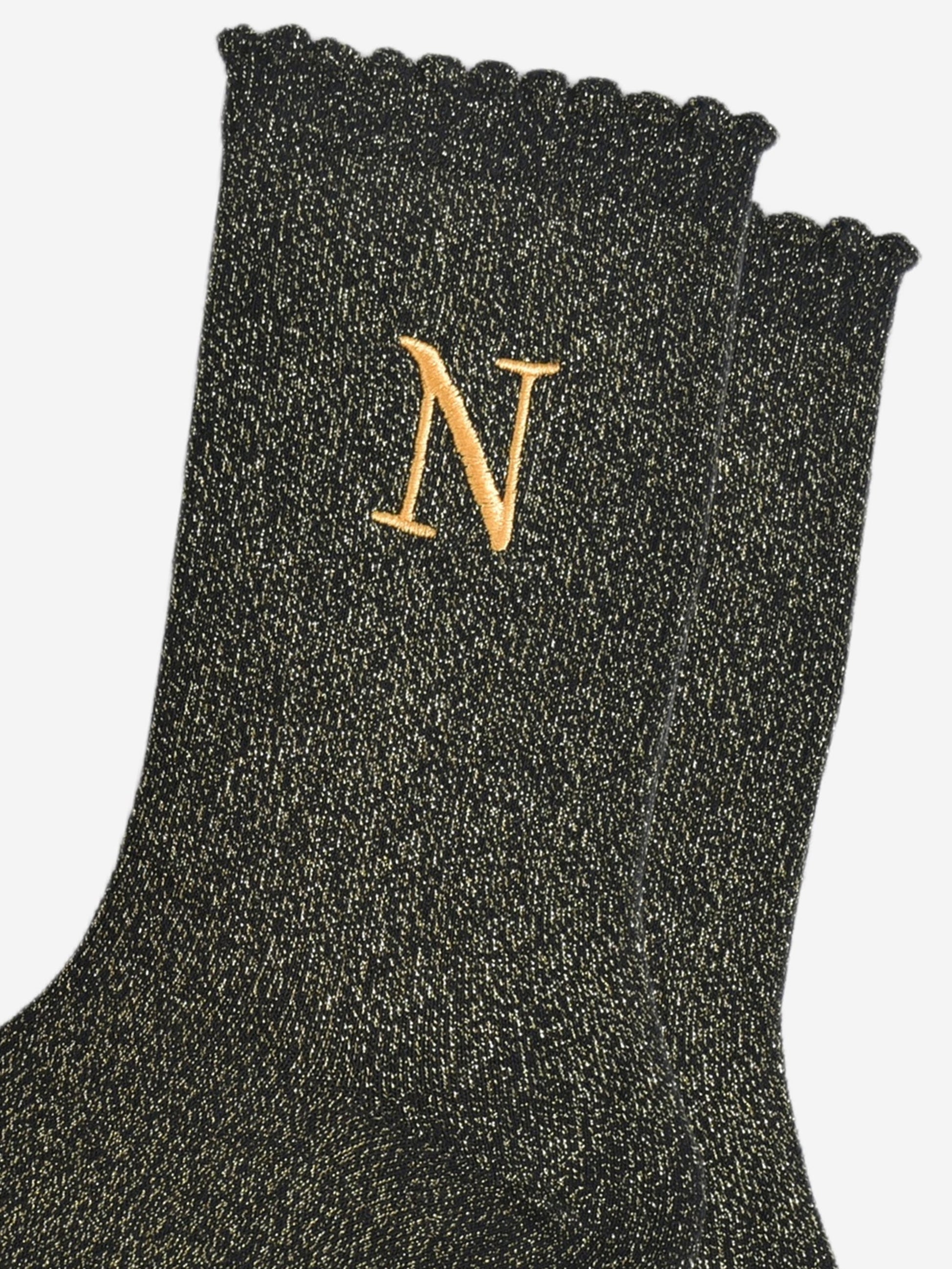 close up of the gold embroidered capital letter n on the ankle of the socks