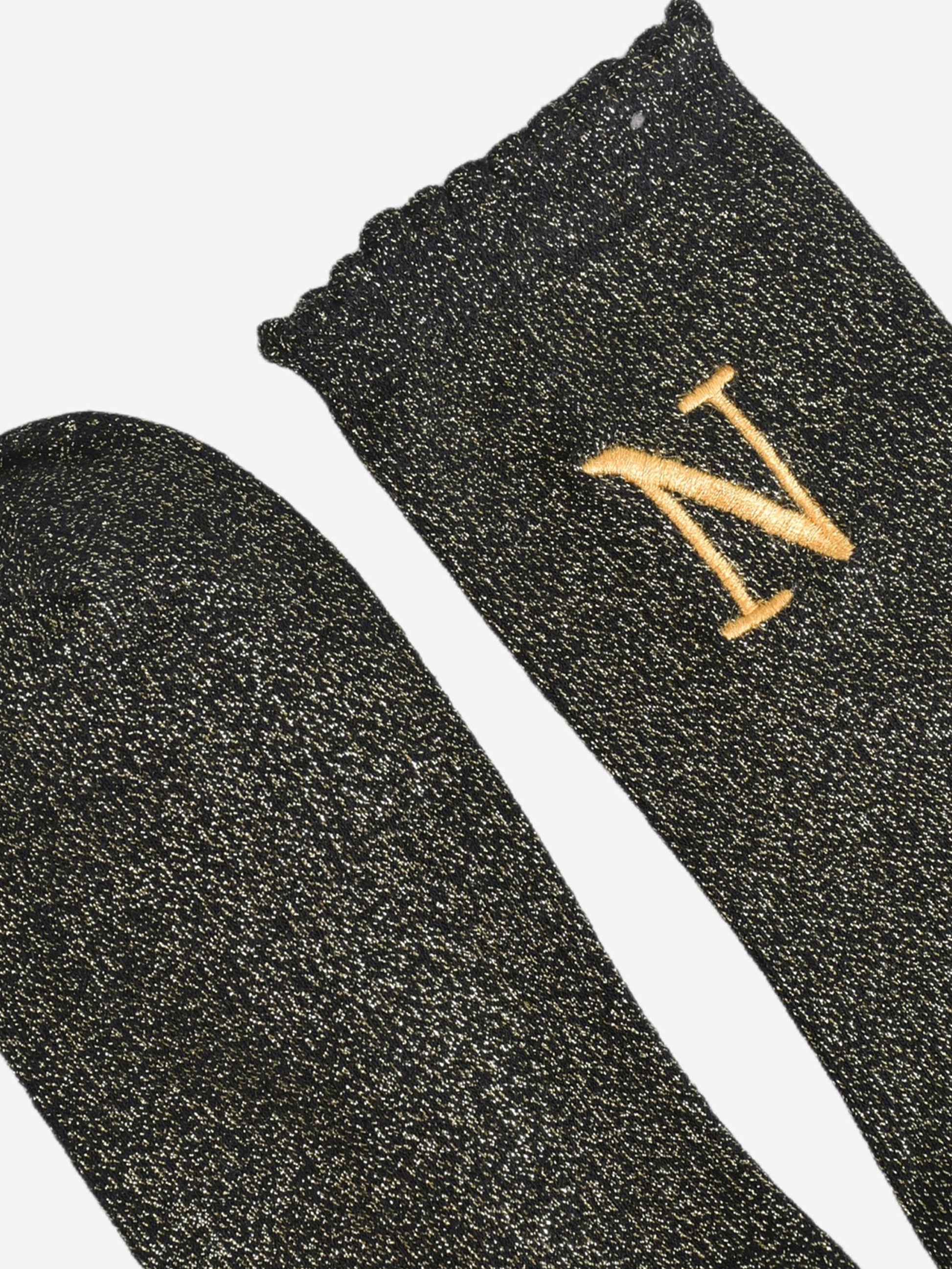 close up of the scalloped cuff on the socks, the toe is the same black and gold as the rest of the socks