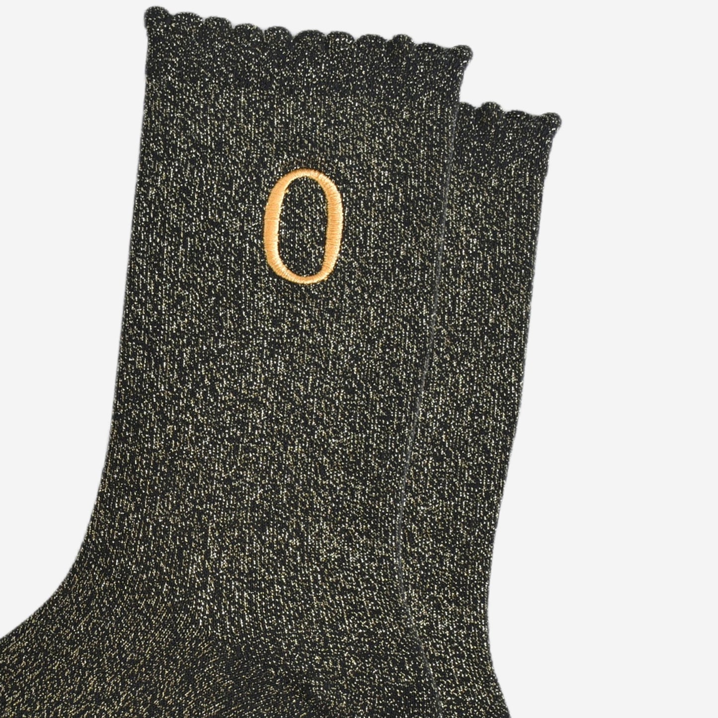 close up of the gold embroidered capital letter o on the ankle of the socks