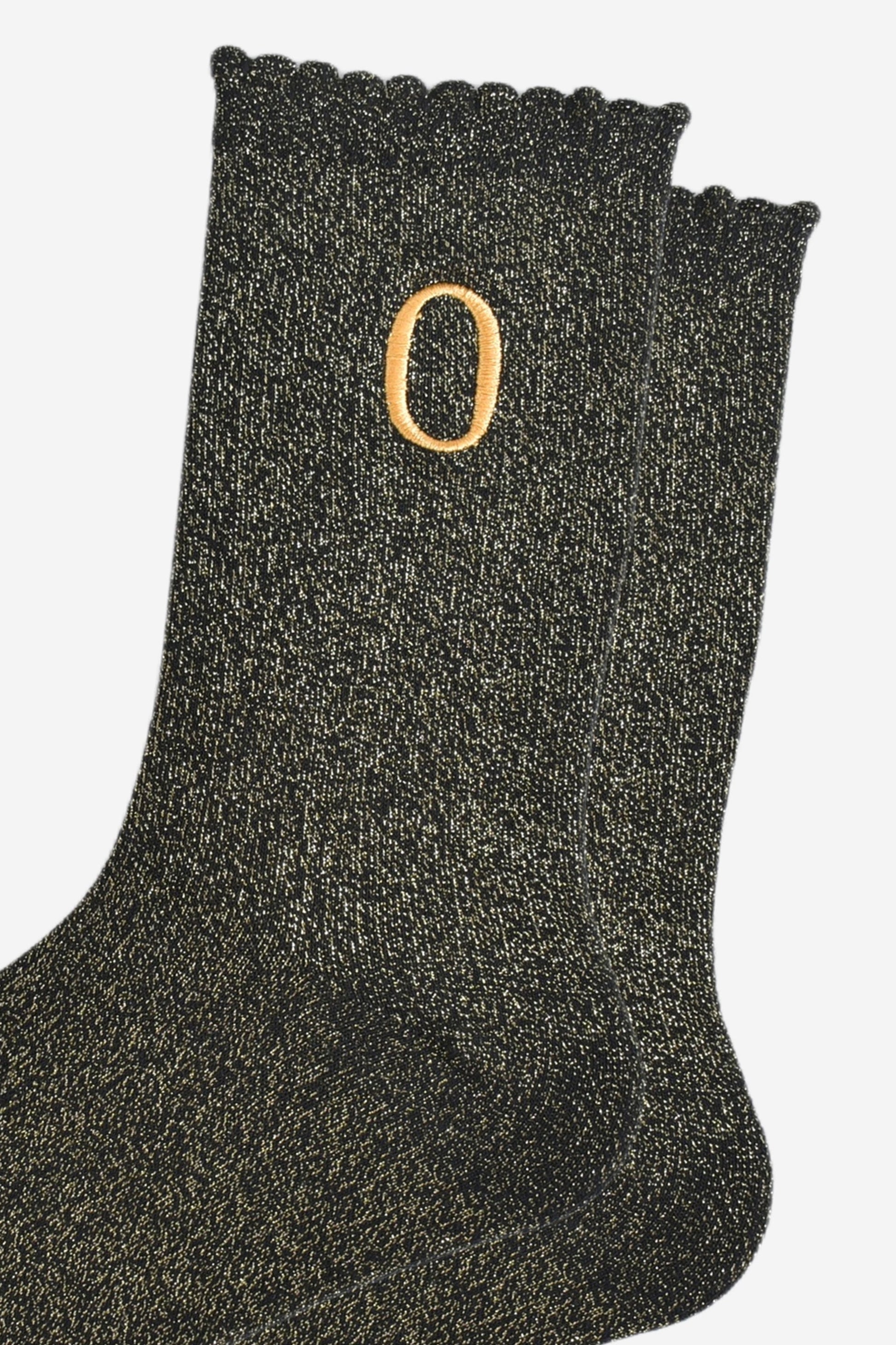 close up of the gold embroidered capital letter o on the ankle of the socks