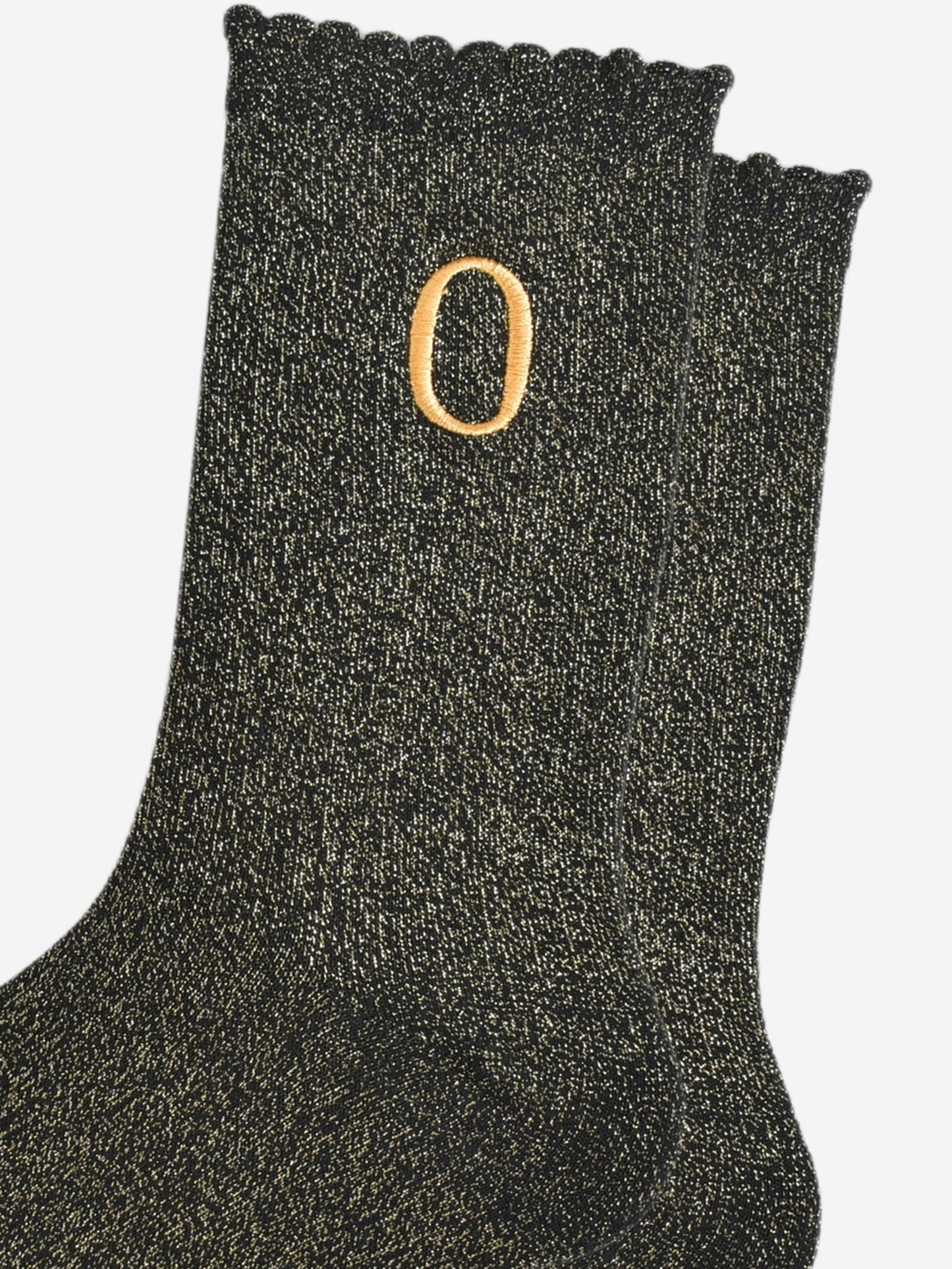 close up of the gold embroidered capital letter o on the ankle of the socks