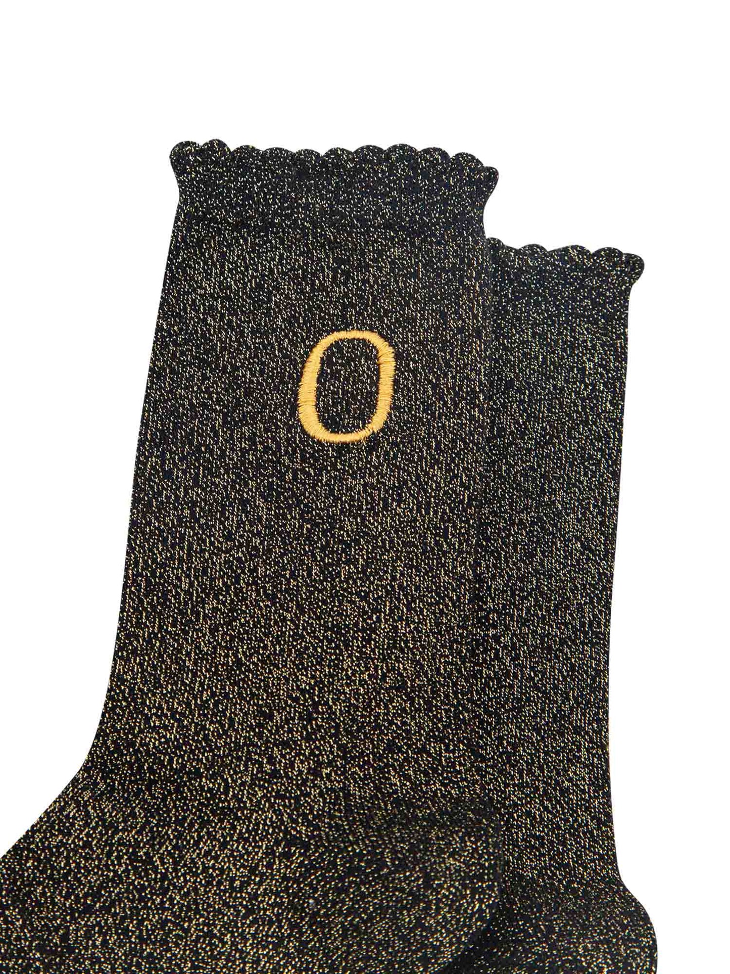 close up of the gold embroidered capital letter o on the ankle of the socks