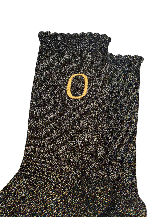 close up of the gold embroidered capital letter o on the ankle of the socks
