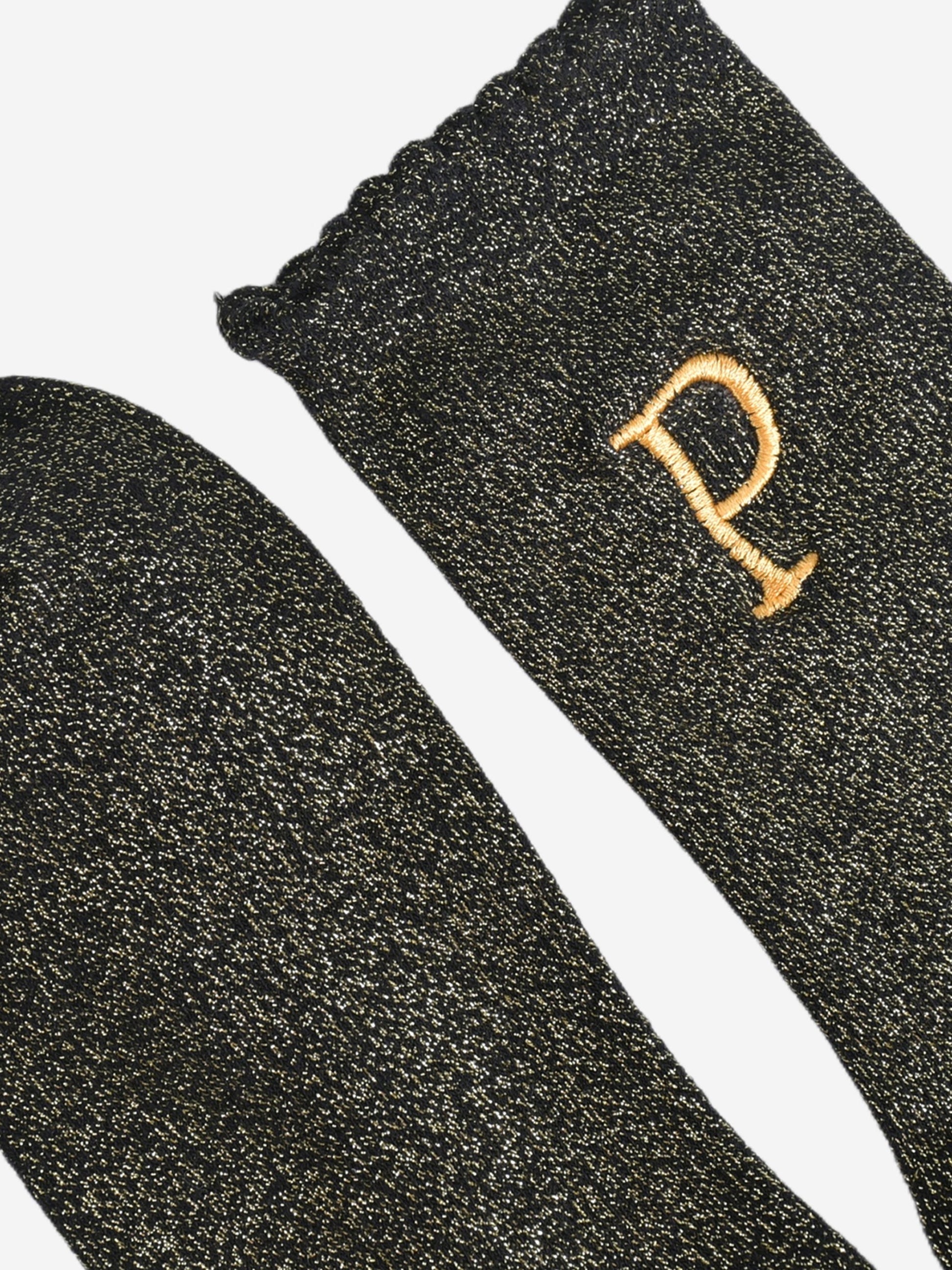 close up of the scalloped cuff on the socks, the toe is the same black and gold as the rest of the socks