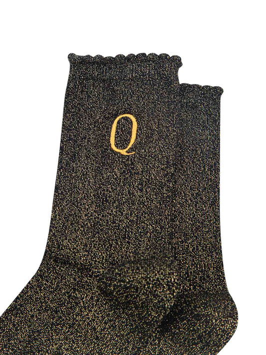 close up of the gold embroidered capital letter q on the ankle of the socks