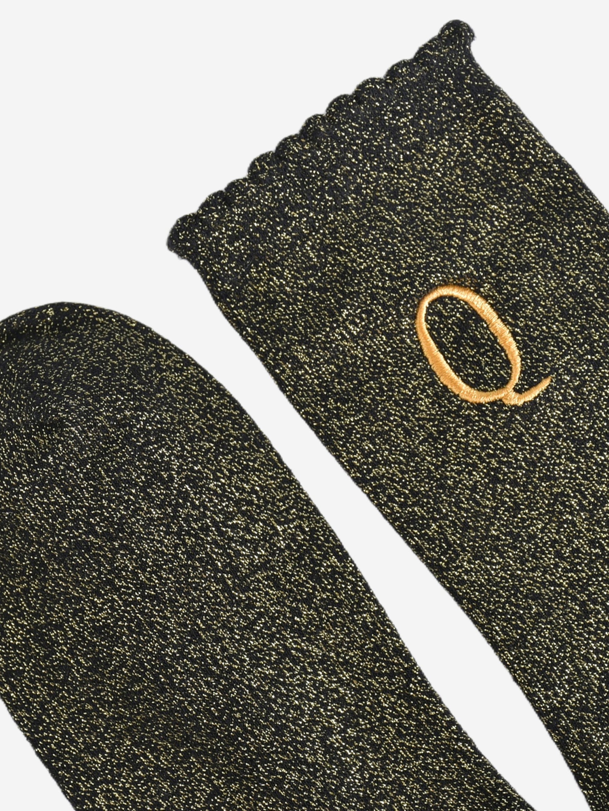 close up of the scalloped cuff on the socks, the toe is the same black and gold as the rest of the socks