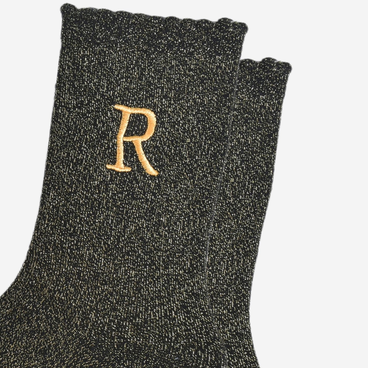 close up of the gold embroidered capital letter r on the ankle of the socks