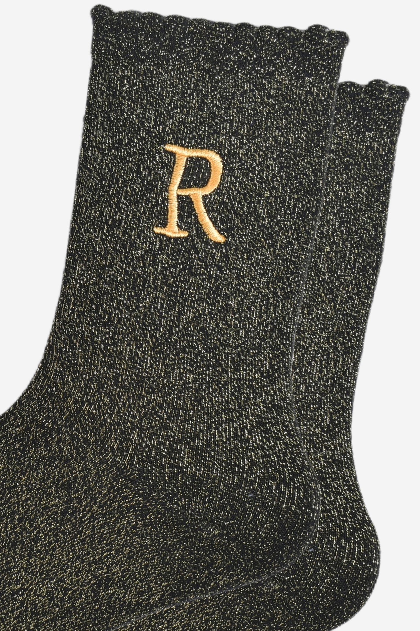 close up of the gold embroidered capital letter r on the ankle of the socks