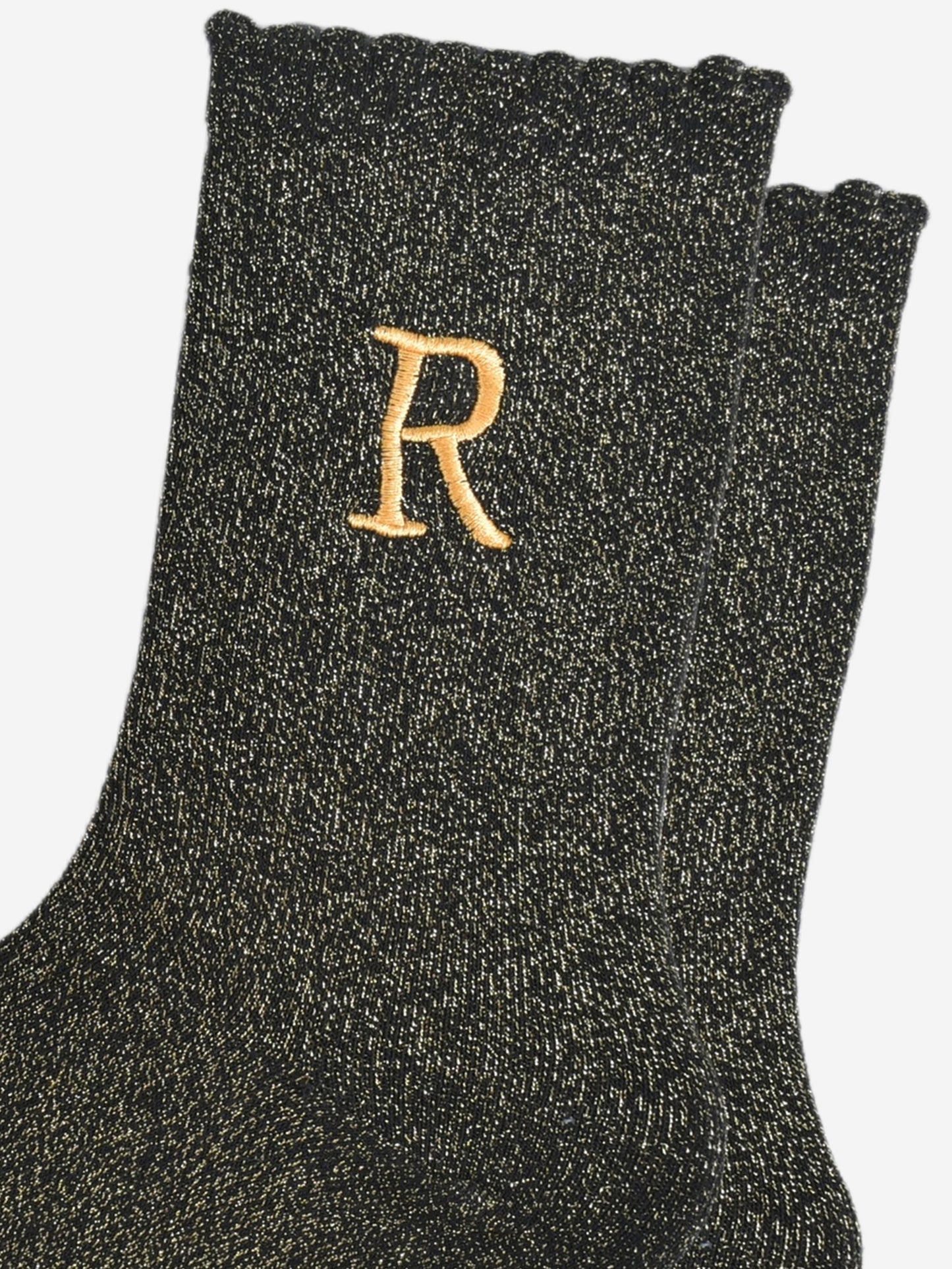 close up of the gold embroidered capital letter r on the ankle of the socks