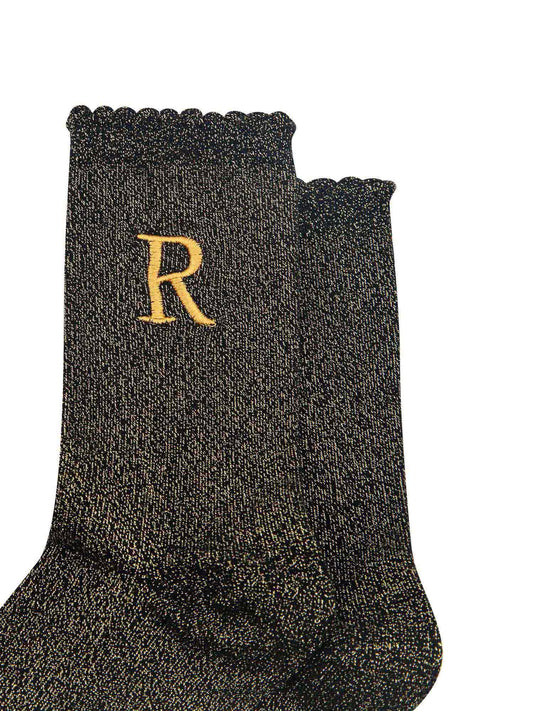 close up of the gold embroidered capital letter r on the ankle of the socks
