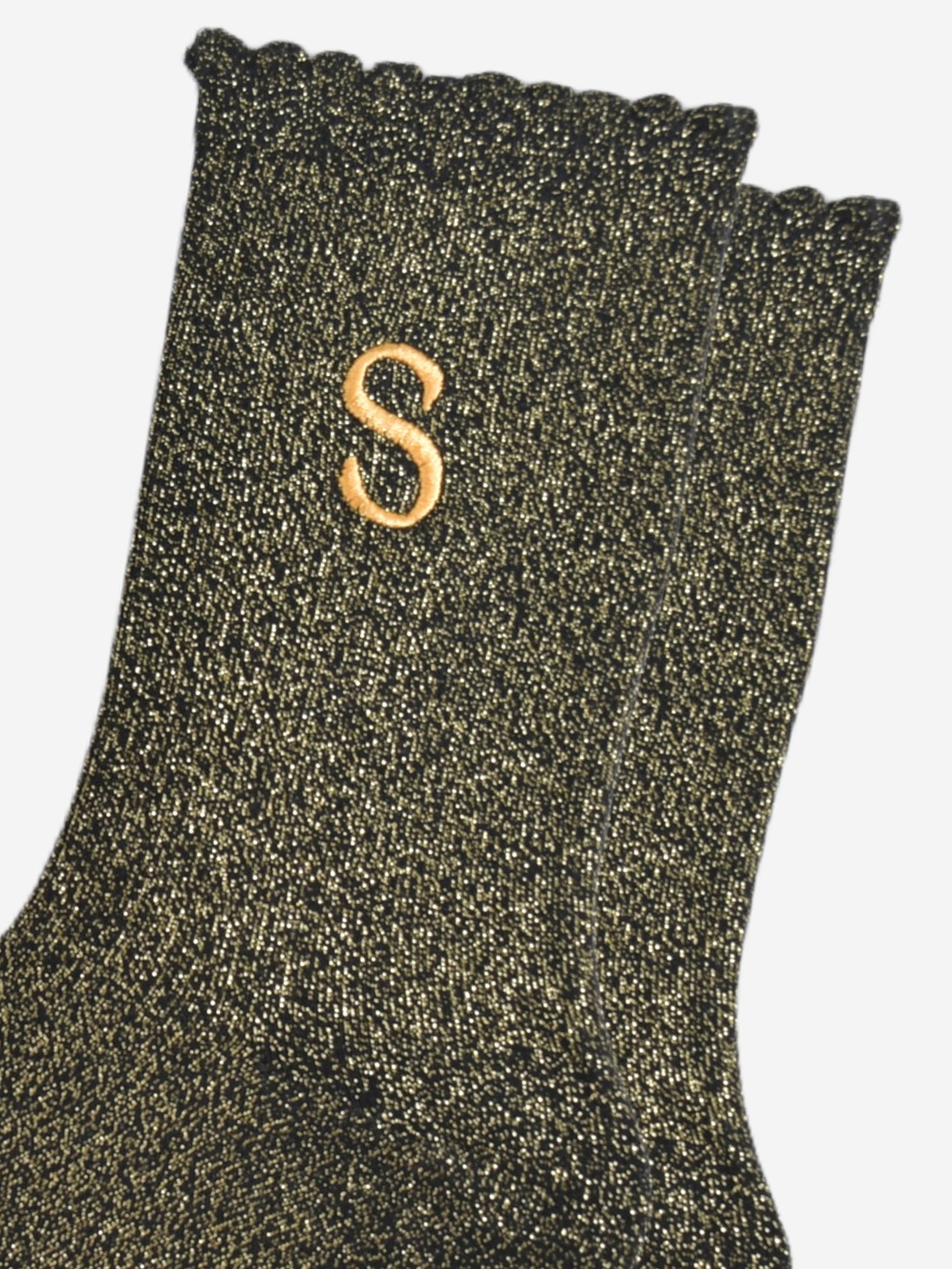 close up of the gold embroidered capital letter s on the ankle of the socks