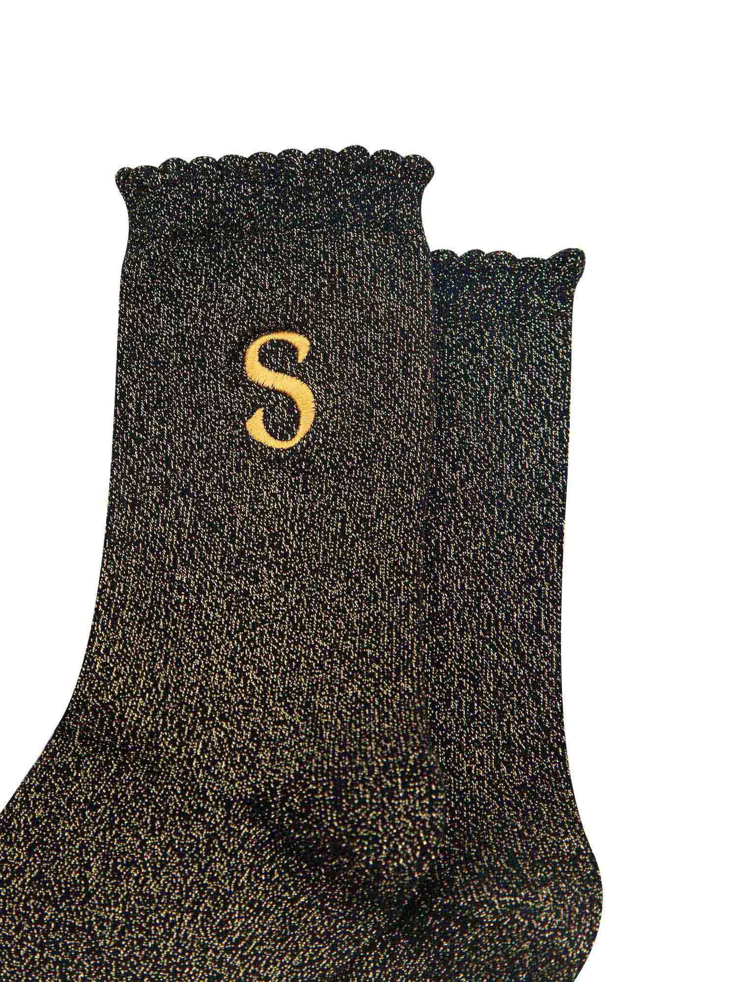 close up of the gold embroidered capital letter s on the ankle of the socks