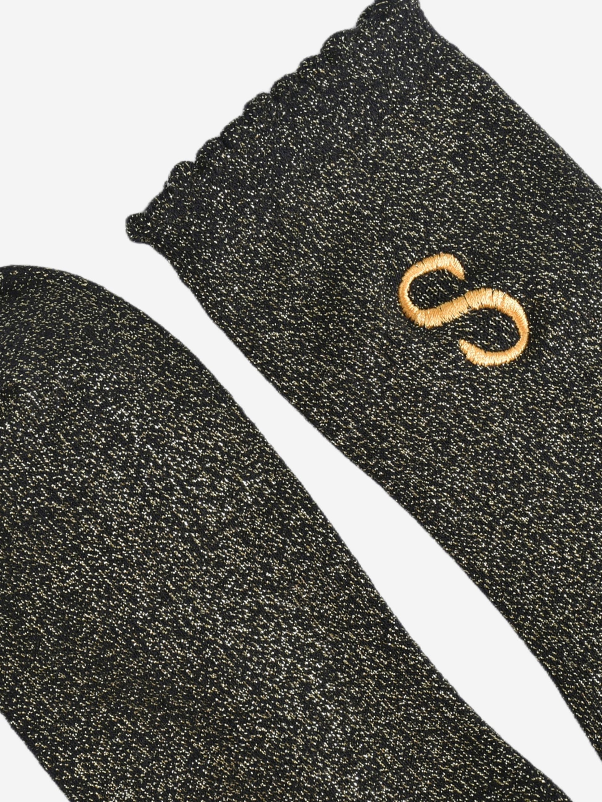 close up of the scalloped cuff on the socks, the toe is the same black and gold as the rest of the socks