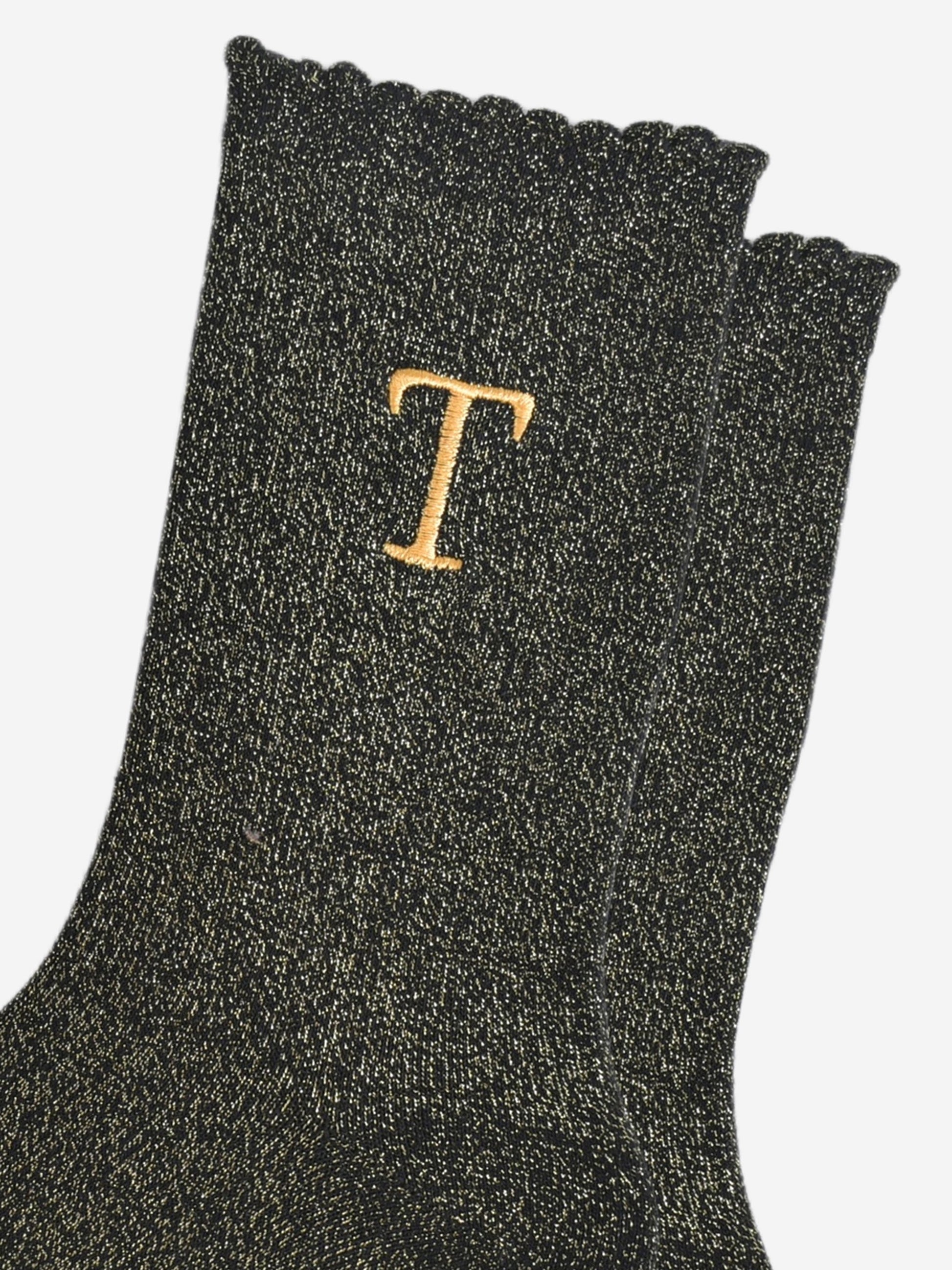 close up of the gold embroidered capital letter t on the ankle of the socks