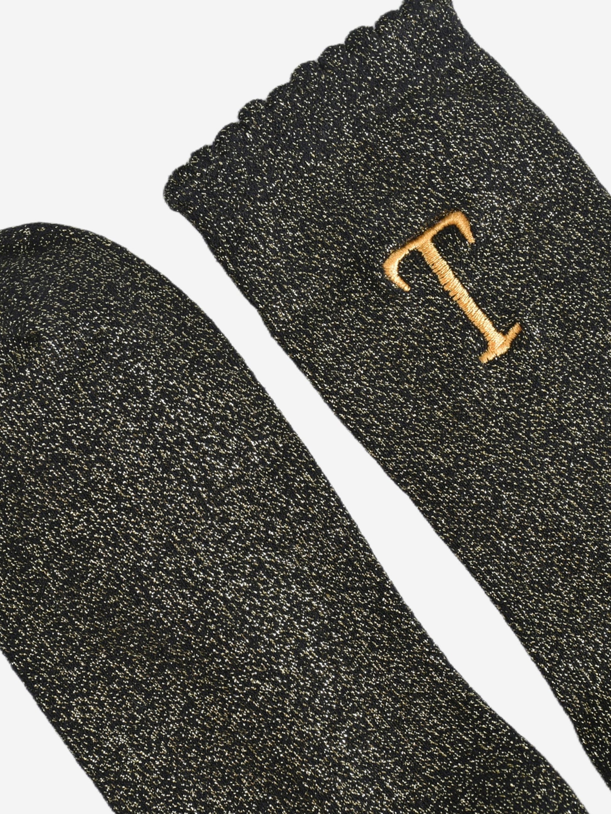 close up of the scalloped cuff on the socks, the toe is the same black and gold as the rest of the socks