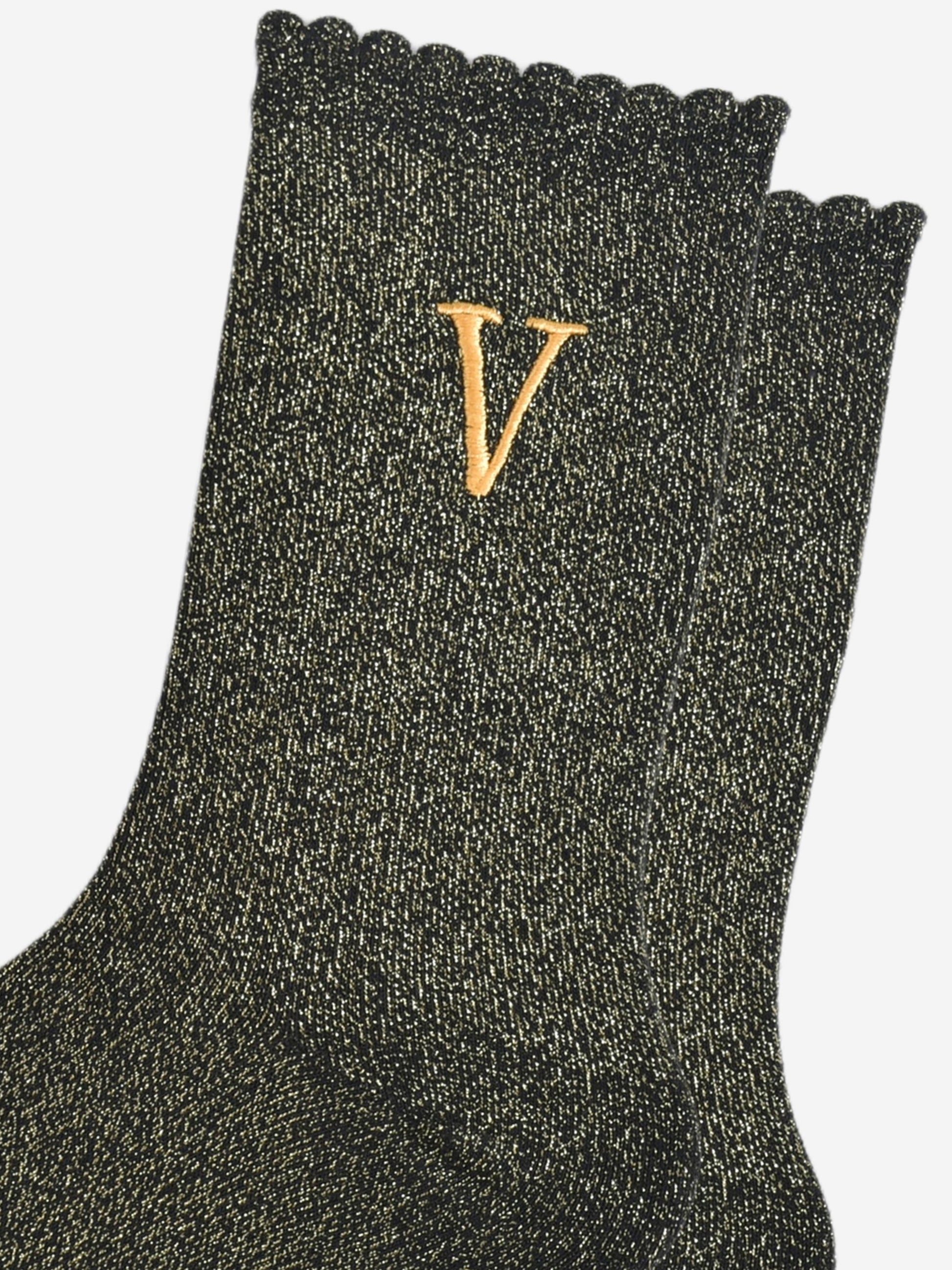 close up of the gold embroidered capital letter v on the ankle of the socks