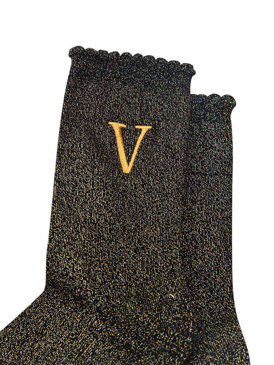 close up of the gold embroidered capital letter v on the ankle of the socks