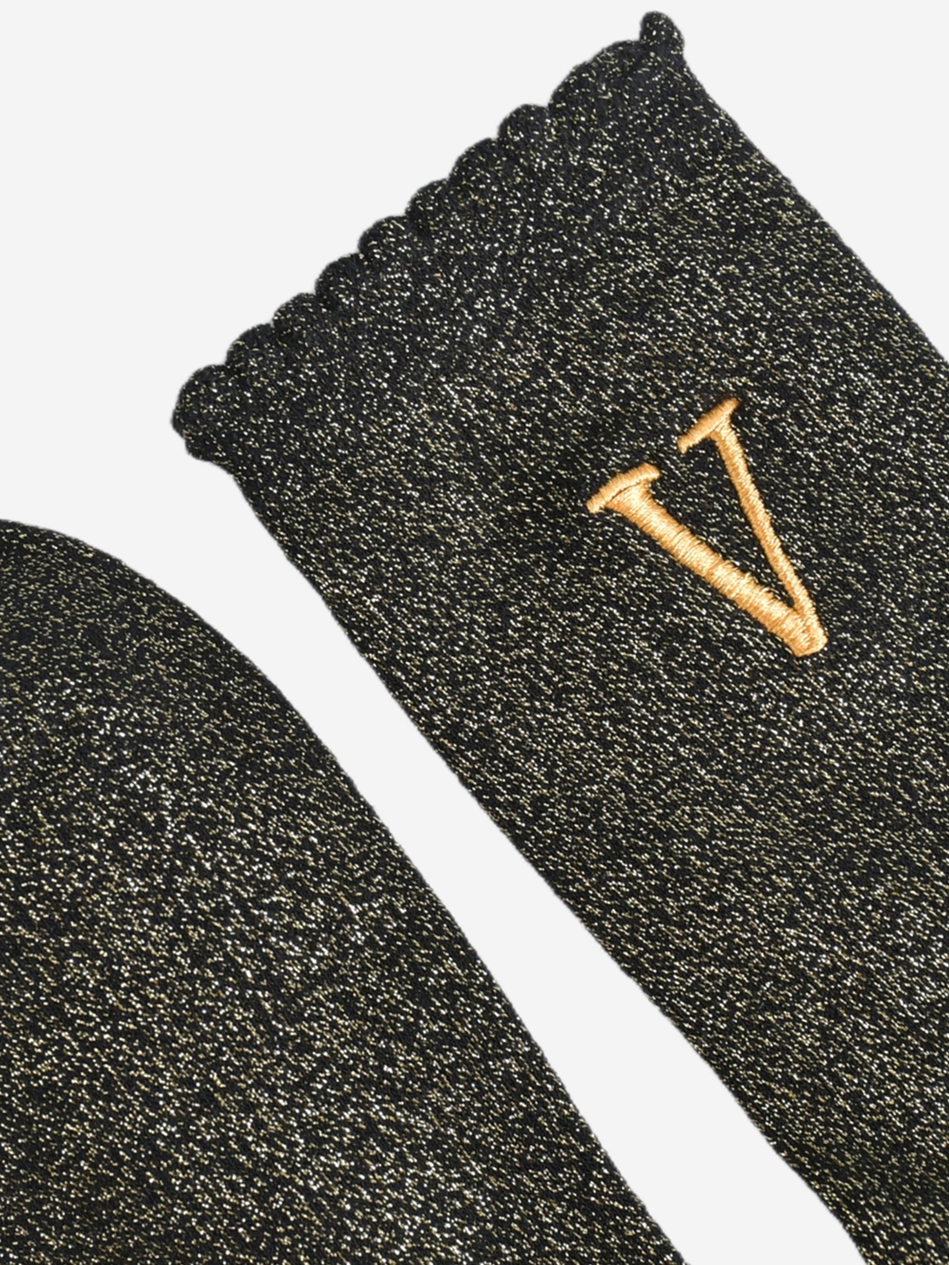 close up of the scalloped cuff on the socks, the toe is the same black and gold as the rest of the socks