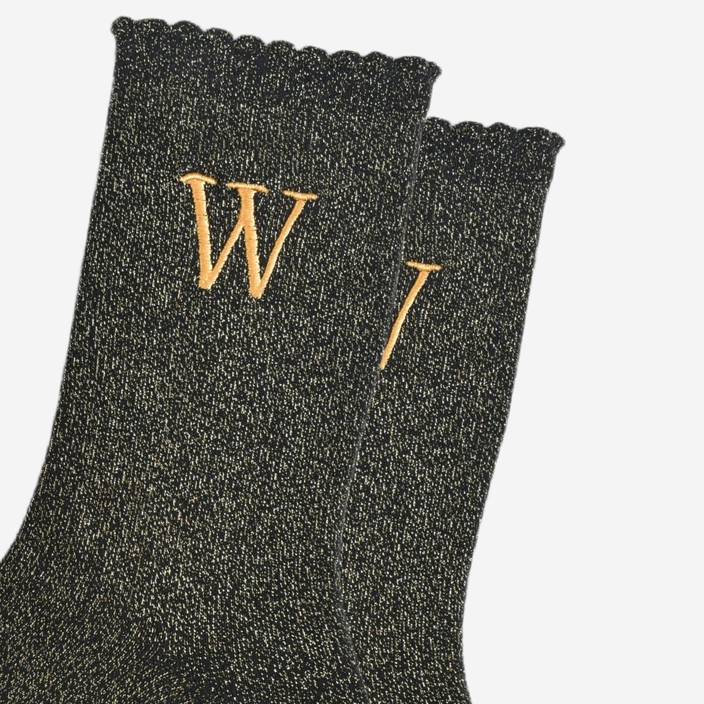 close up of the gold embroidered capital letter w on the ankle of the socks