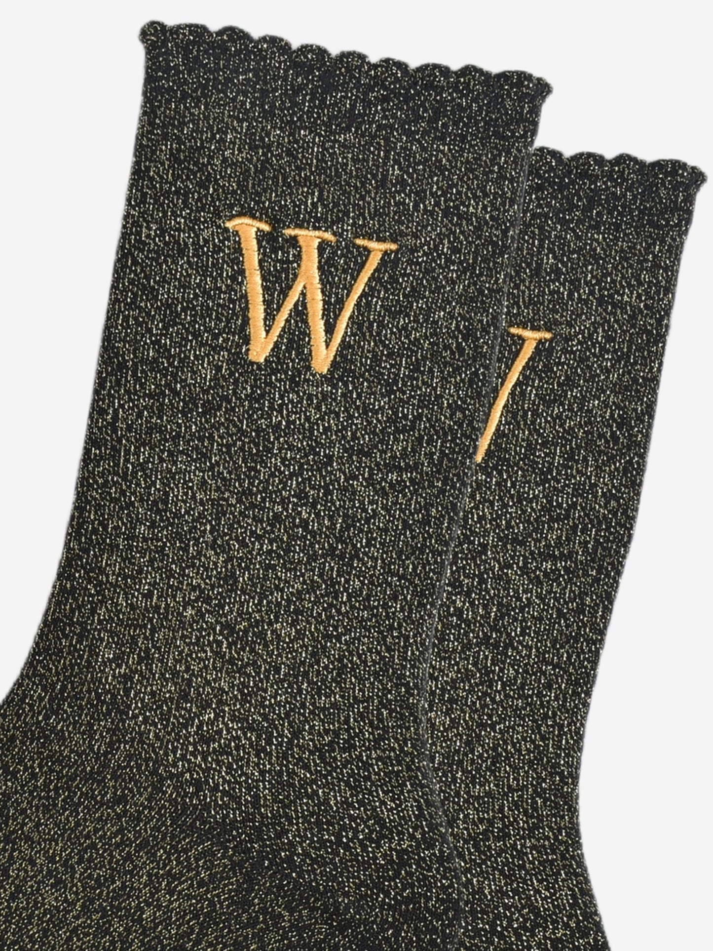 close up of the gold embroidered capital letter w on the ankle of the socks